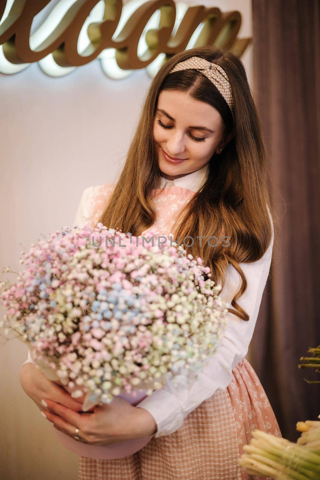 Woman make spring bouquet. Female florist wrapping beautiful bouquet of spring flowers in pack paper on the table. Beautiful flower composition