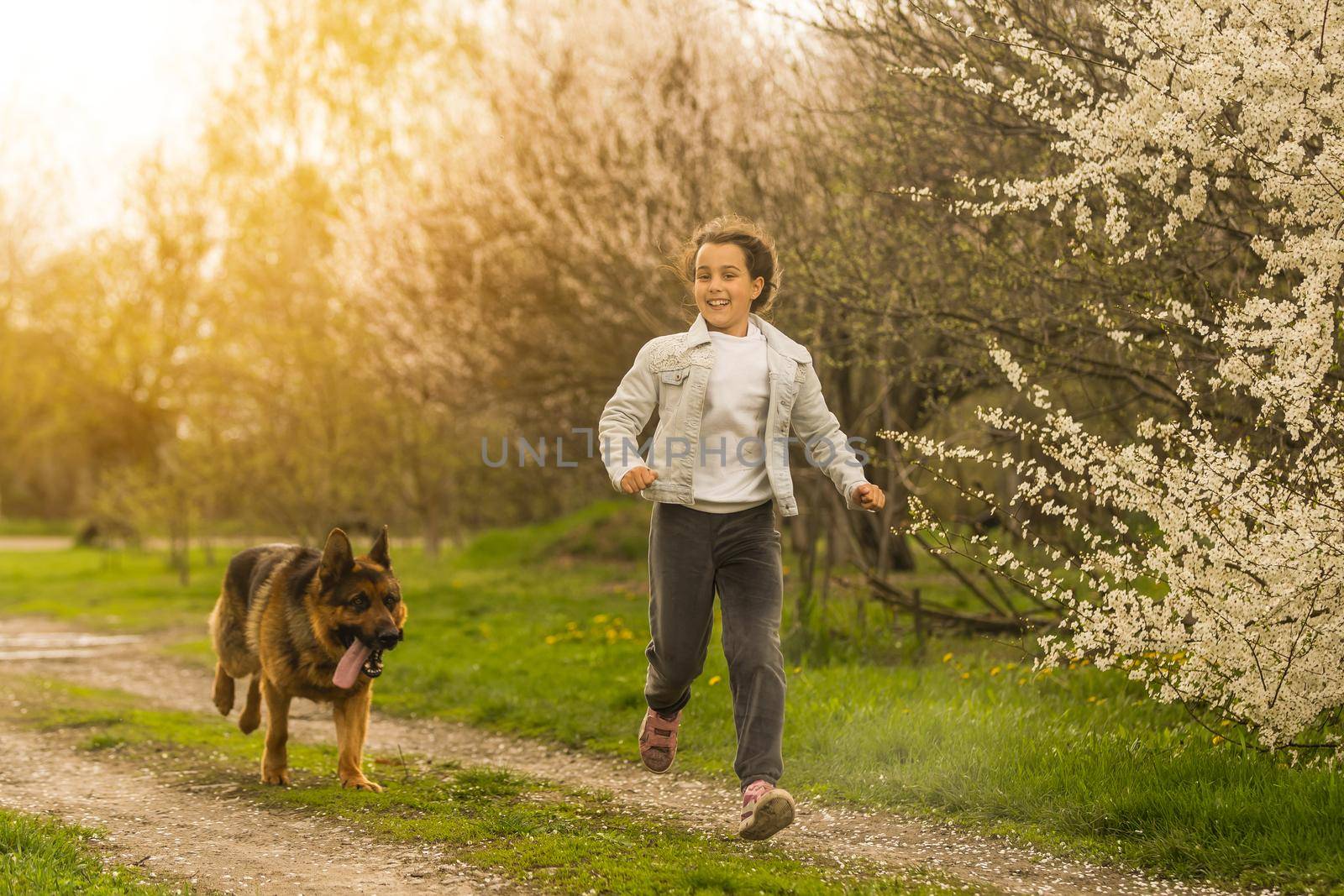 little girl running with a dog in a flower garden.