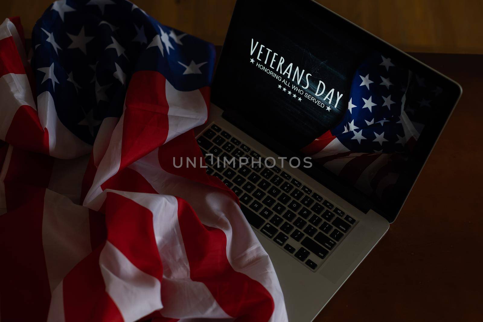 veterans day written in laptop with flag of the United States, on a rustic wooden background by Andelov13