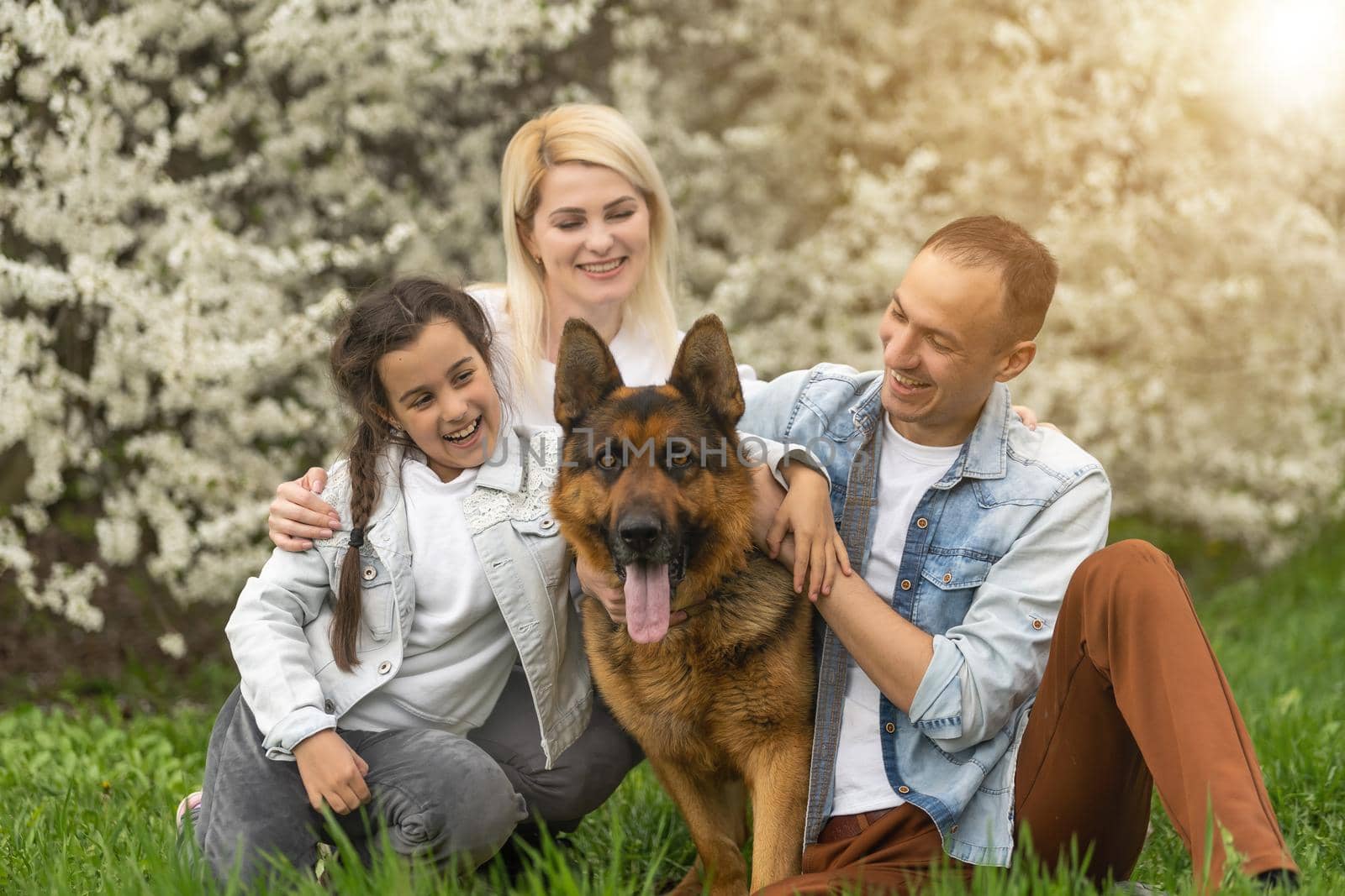 Happy family outdoors spending time together. Father, mother and daughter are having fun on a green floral grass