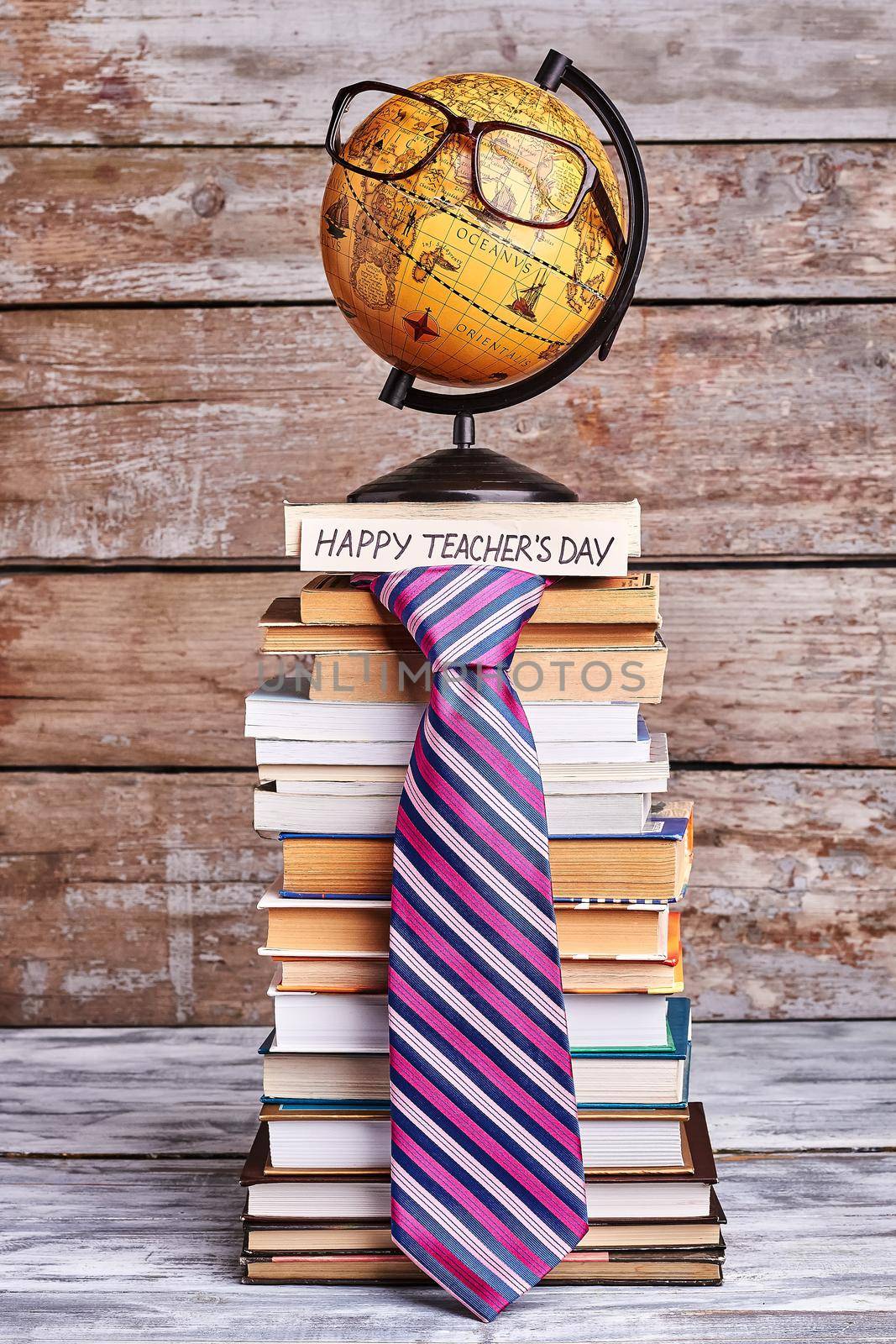 Glasses on globe and tie. Stack of books and card. Congratulate geography teacher.