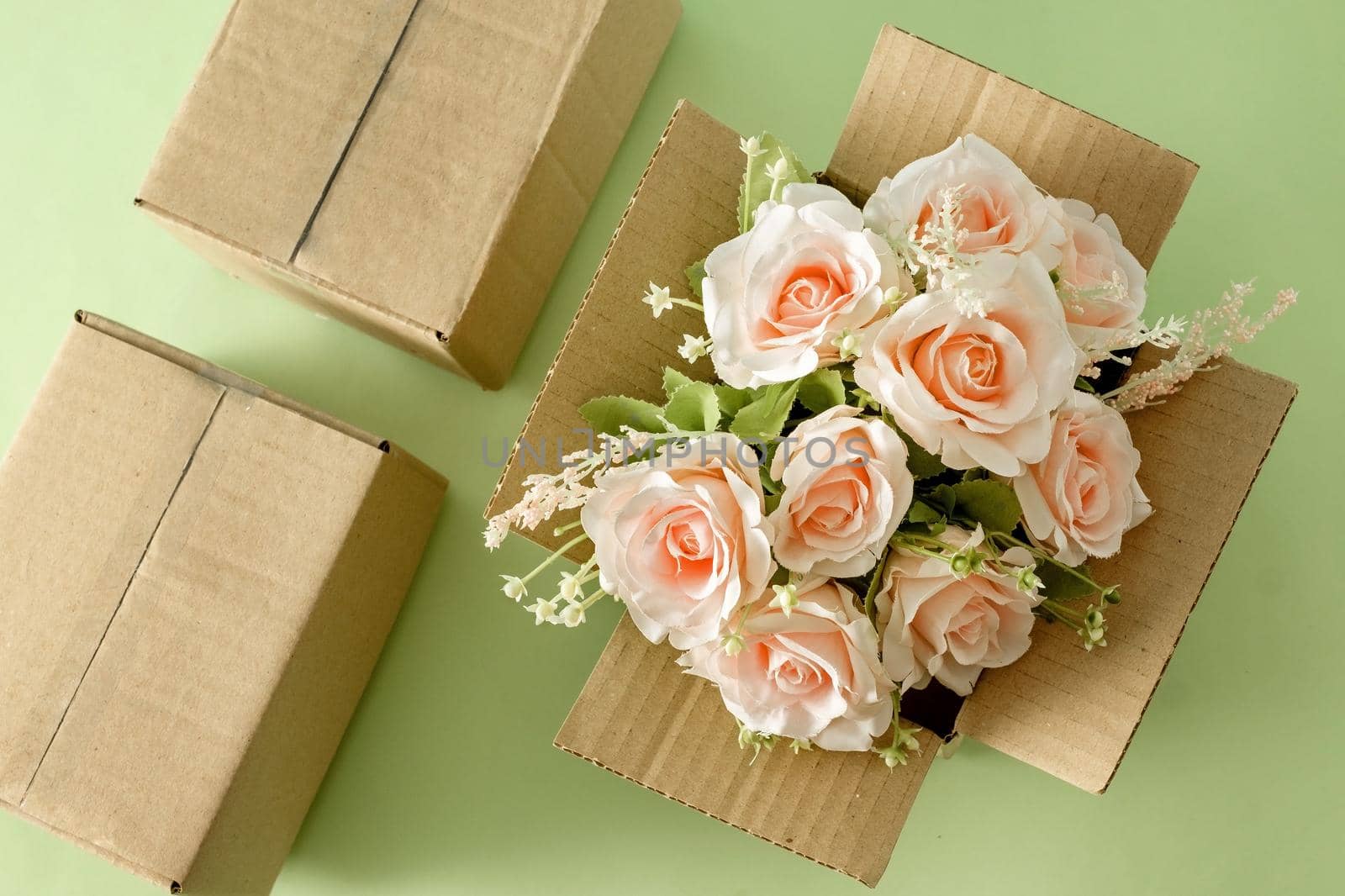 A beautiful blooming bouquet of pink roses in a parcel delivery cardboard box. Gift holiday concept and logistics service.
