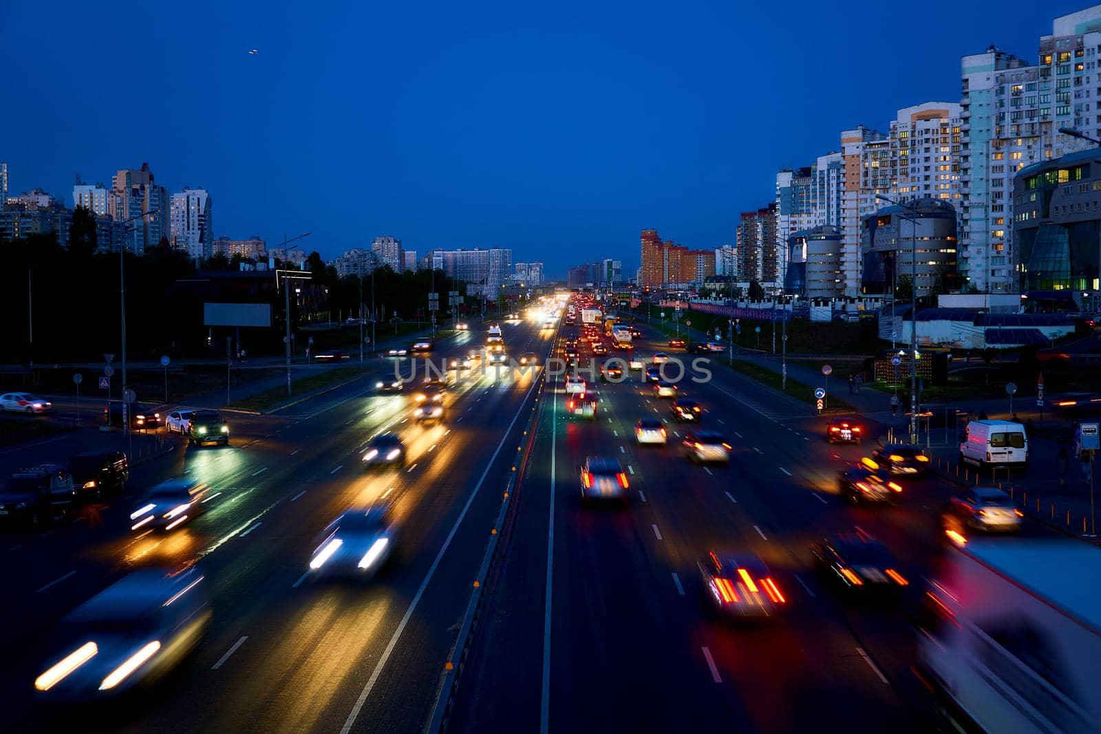 a broad road in a town or city, typically having trees at regular intervals along its sides. night shining avenue with moving cars and lights.