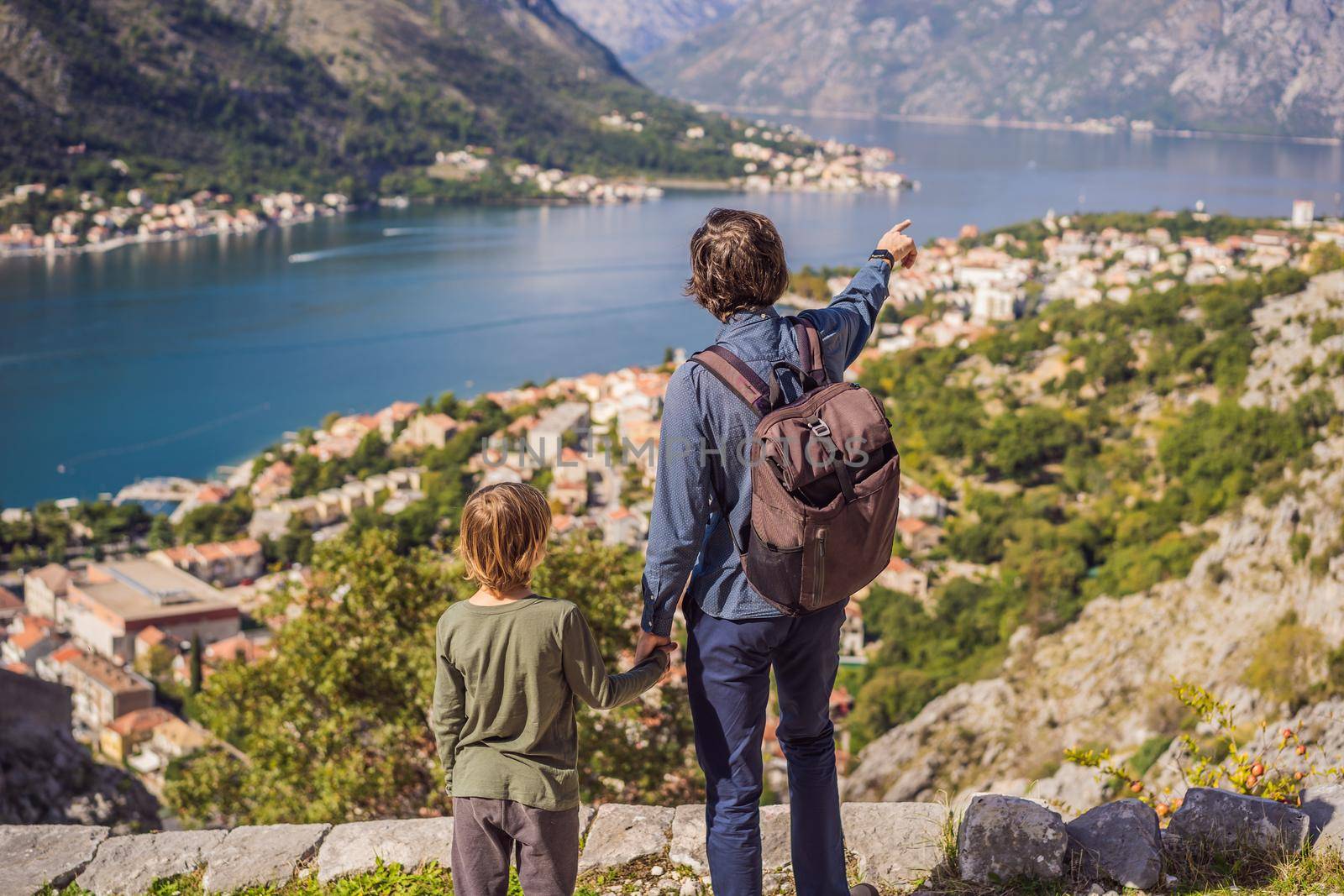 Dad and son travellers enjoys the view of Kotor. Montenegro. Bay of Kotor, Gulf of Kotor, Boka Kotorska and walled old city. Travel with kids to Montenegro concept. Fortifications of Kotor is on UNESCO World Heritage List since 1979 by galitskaya