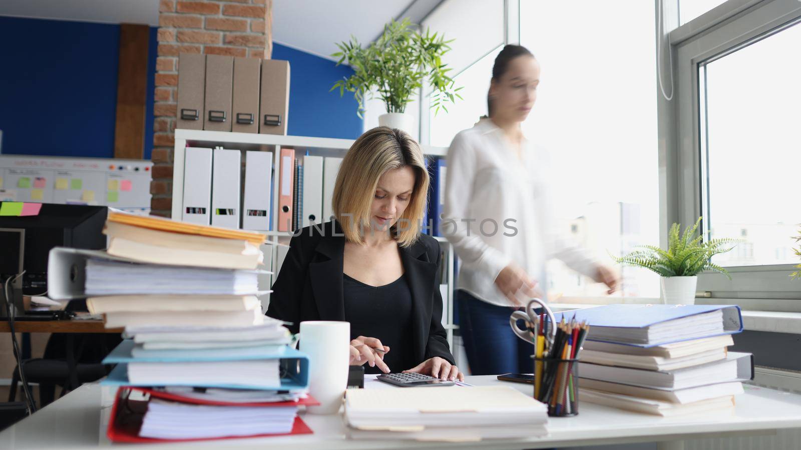 Portrait of young accountant working with papers in office. Woman making annual report. Deadline, fired worker, debt and time management concept