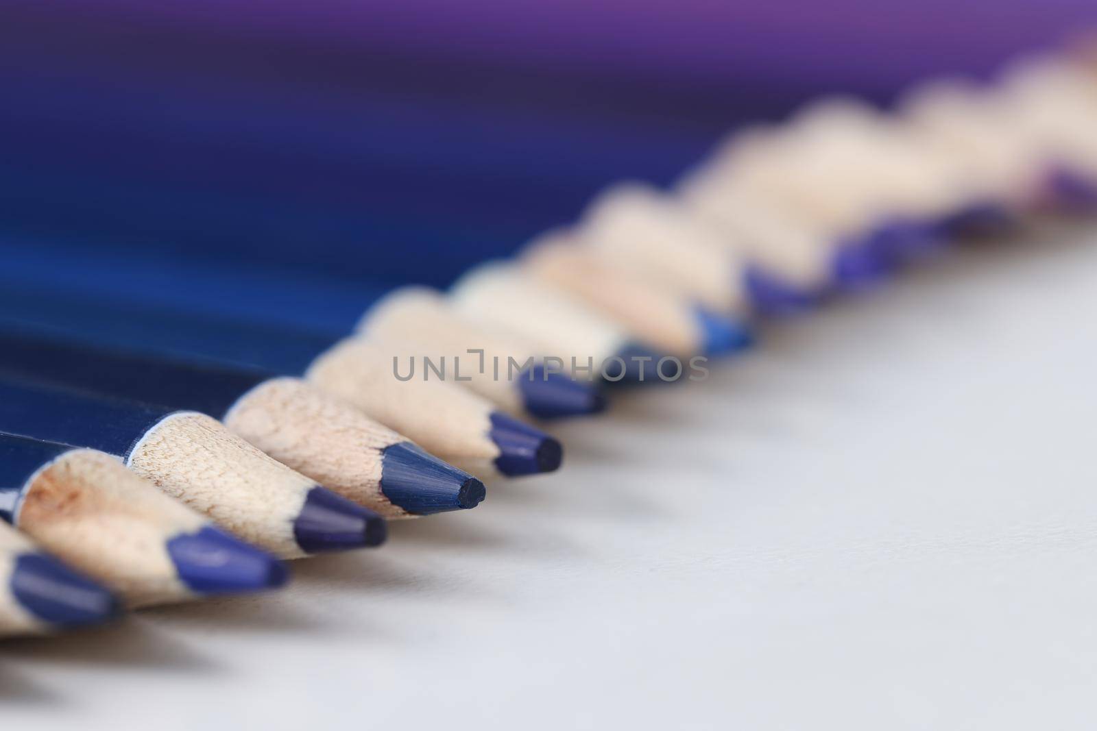 Close-up of set of blue identical pencils lie in raw. Several sharpened pencils of blue color