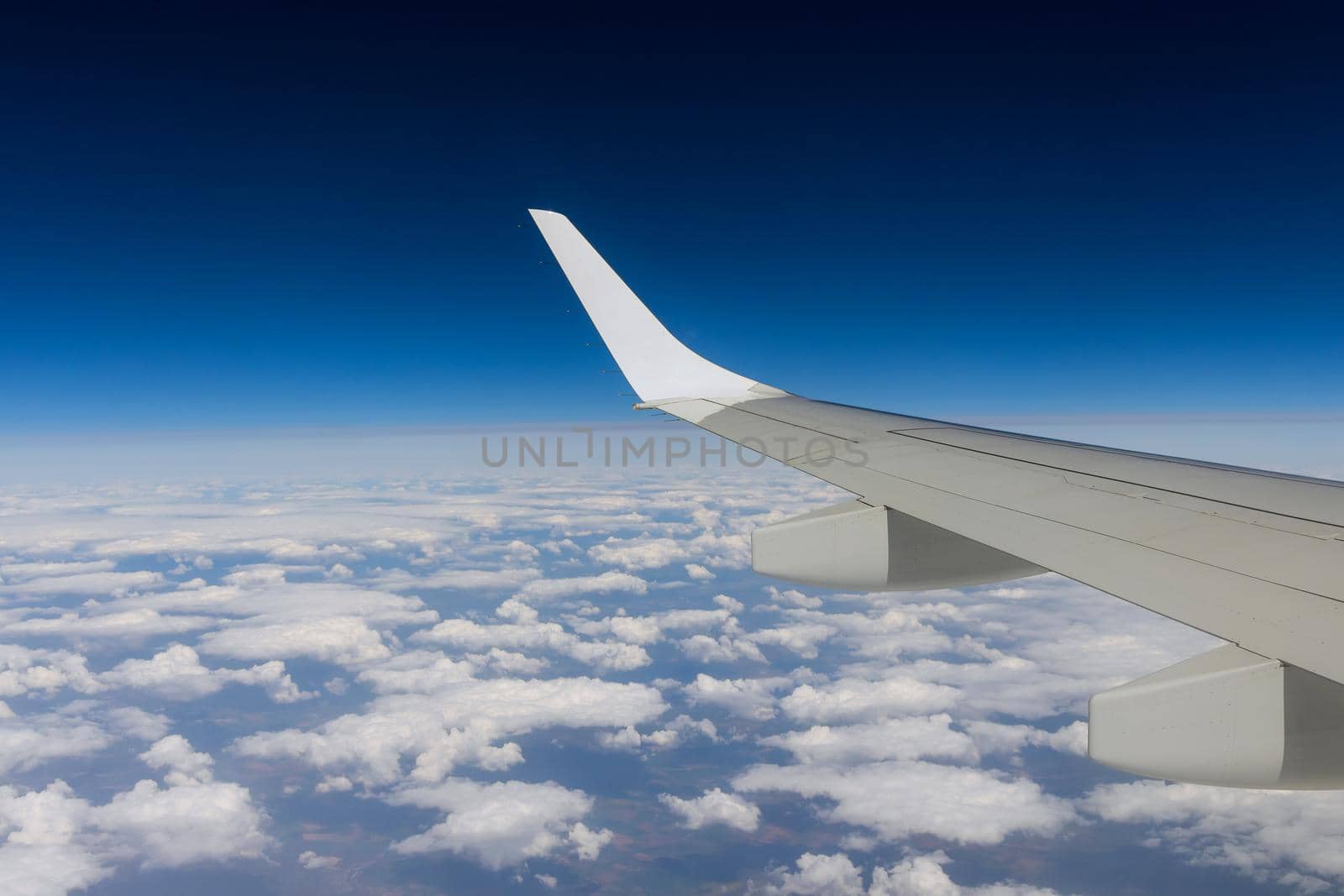 Wing on clouds blue sky with flying view from airplane window by ungvar