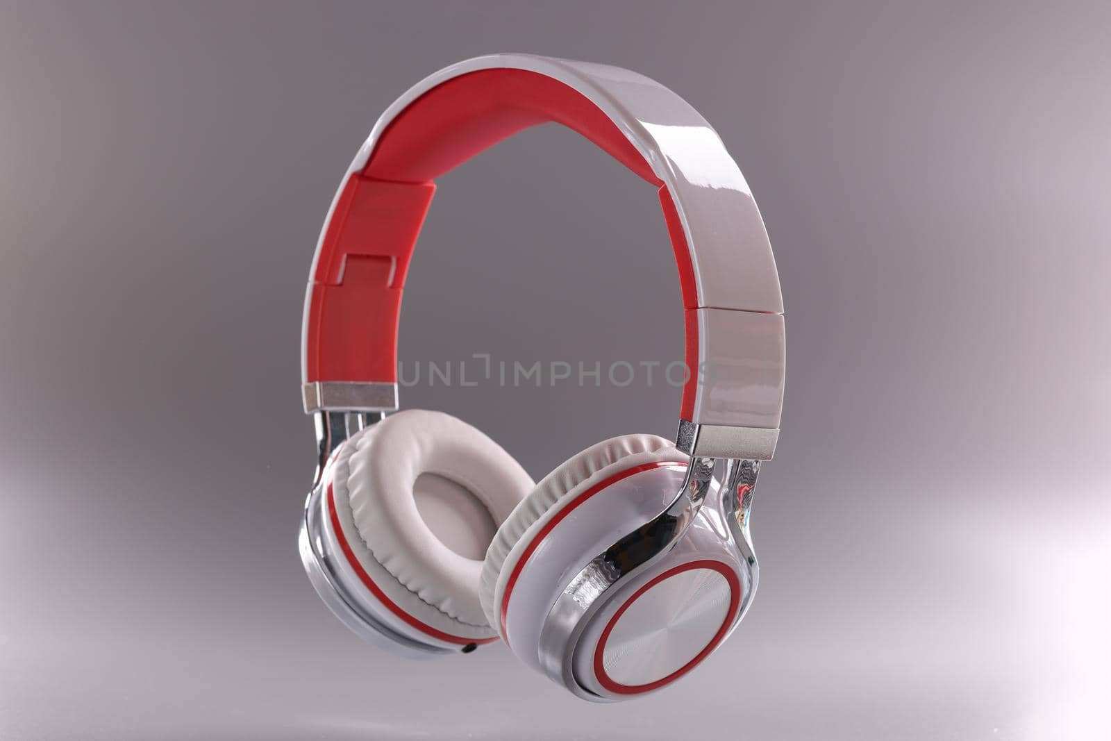 Close-up of modern headphones in red and white colour combination on grey background. Music, sound, technology and dj equipment concept