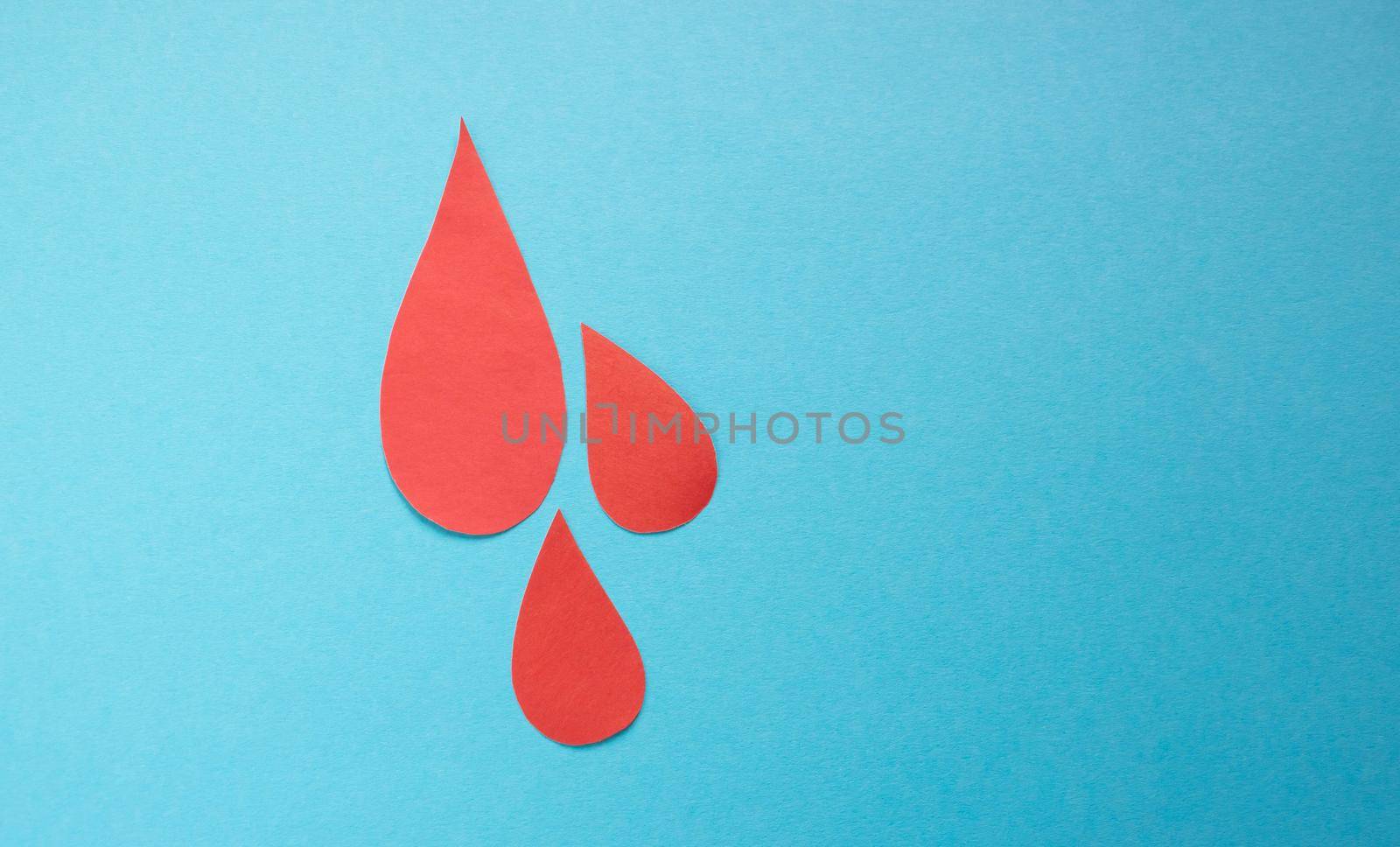 The concept of the World Blood Donor and Hemophilia Day. Red paper drops of blood on a blue background. Place for your text by lapushka62