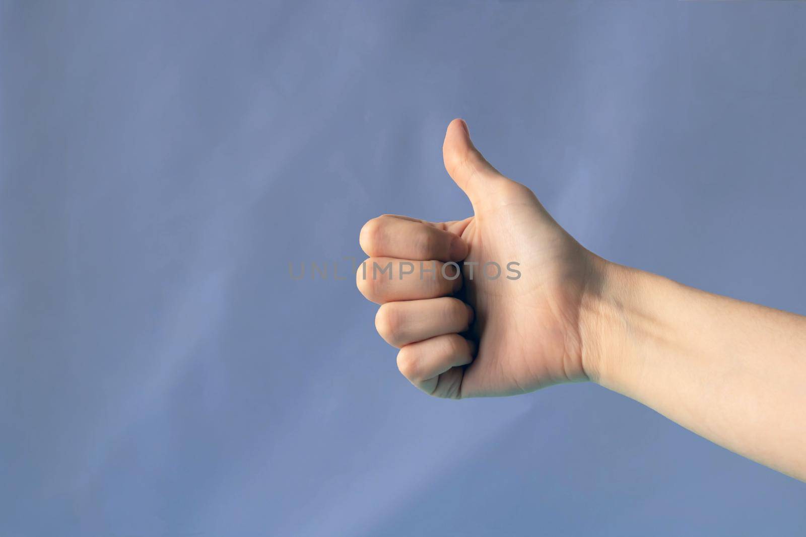 Arm outstretched, fist thumbs up. The gesture highlighted on a lilac background with a cropping contour is very peri. Place for your text by lapushka62