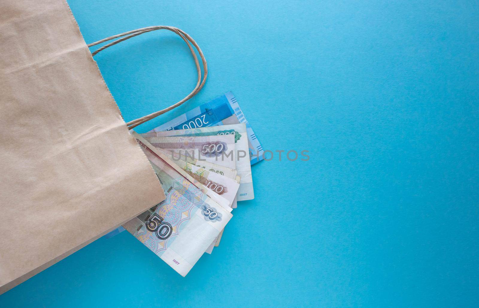 A bundle of Russian money and a paper bag on a blue background. Place for your text by lapushka62