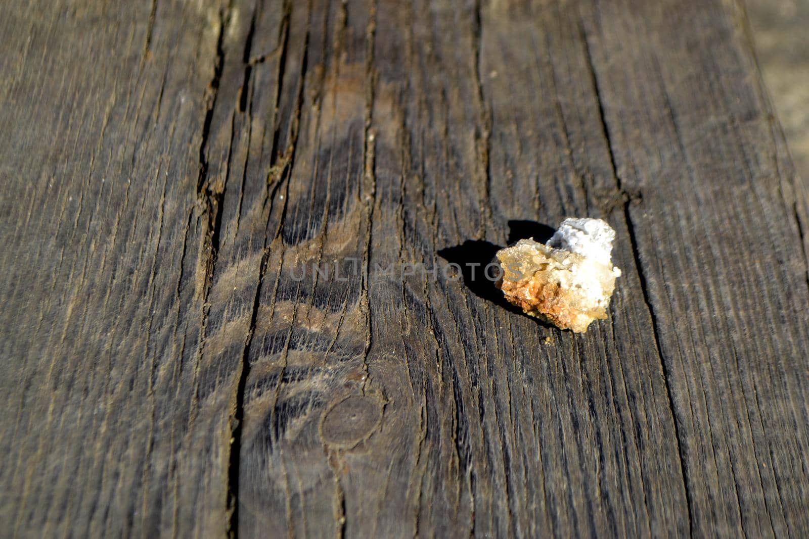 A porcelain bowl in the shape of a heart filled with large crystals of salt on an old weathered board. High quality photo