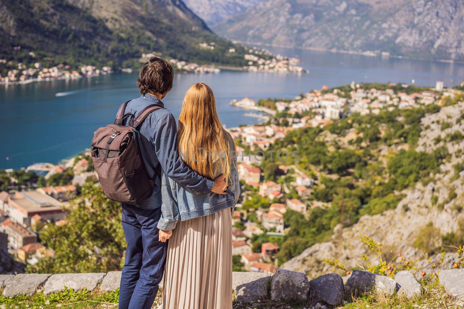 Couple woman and man tourists enjoys the view of Kotor. Montenegro. Bay of Kotor, Gulf of Kotor, Boka Kotorska and walled old city. Travel to Montenegro concept. Fortifications of Kotor is on UNESCO World Heritage List since 1979.