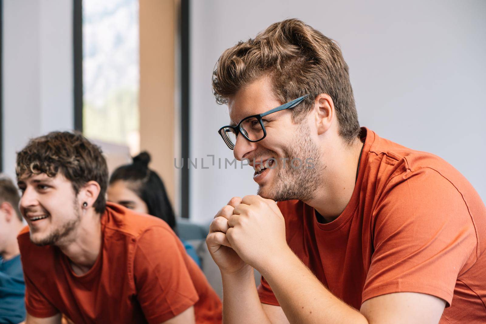 friends concentrating on watching e-sports on TV after their team's victory. group of young people partying at home. leisure concept. happy and cheerful. natural light in the living room at home. trumpet