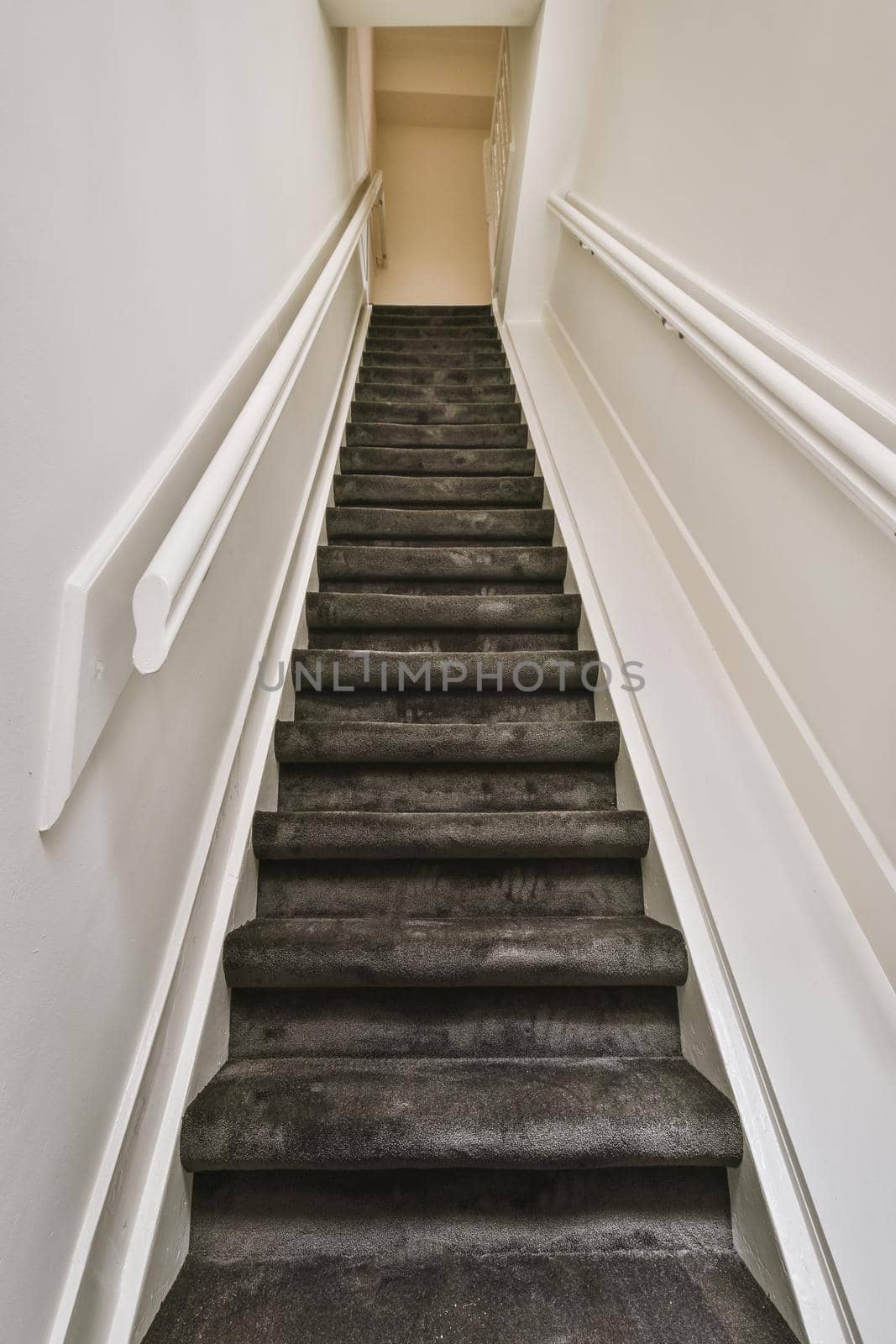 A spacious corridor with a straight carpet staircase by casamedia