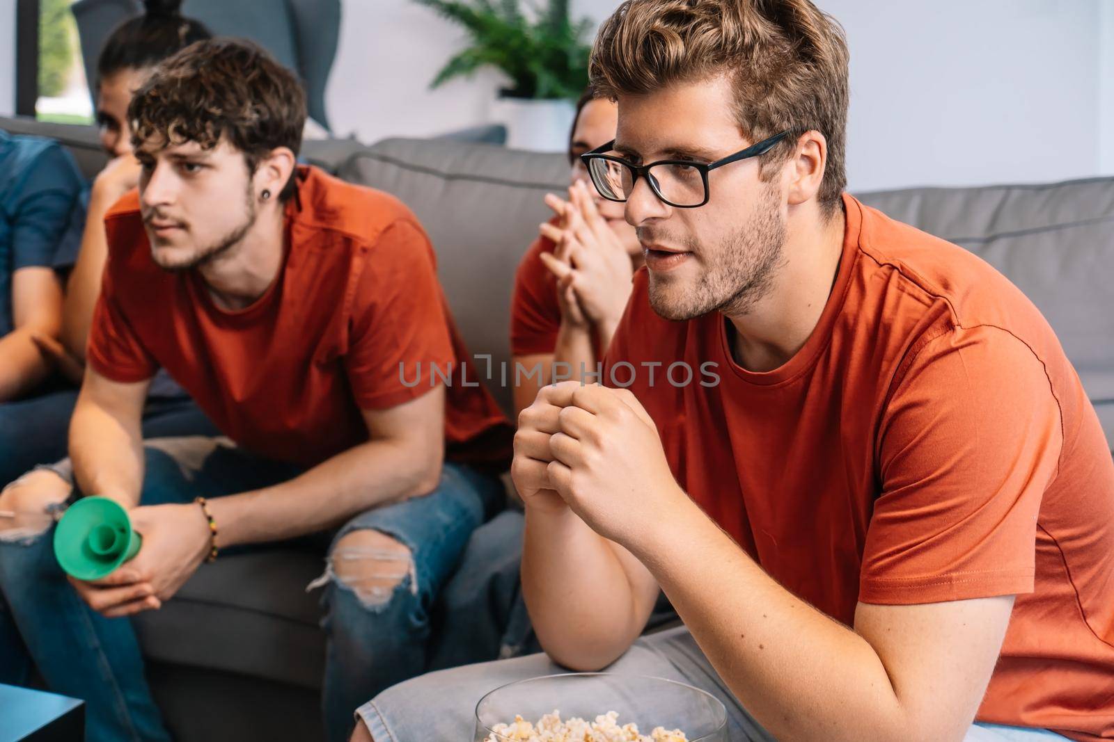 friends concentrating on watching e-sports on TV after their team's victory. group of young people partying at home. leisure concept. happy and cheerful. natural light in the living room at home. trumpet