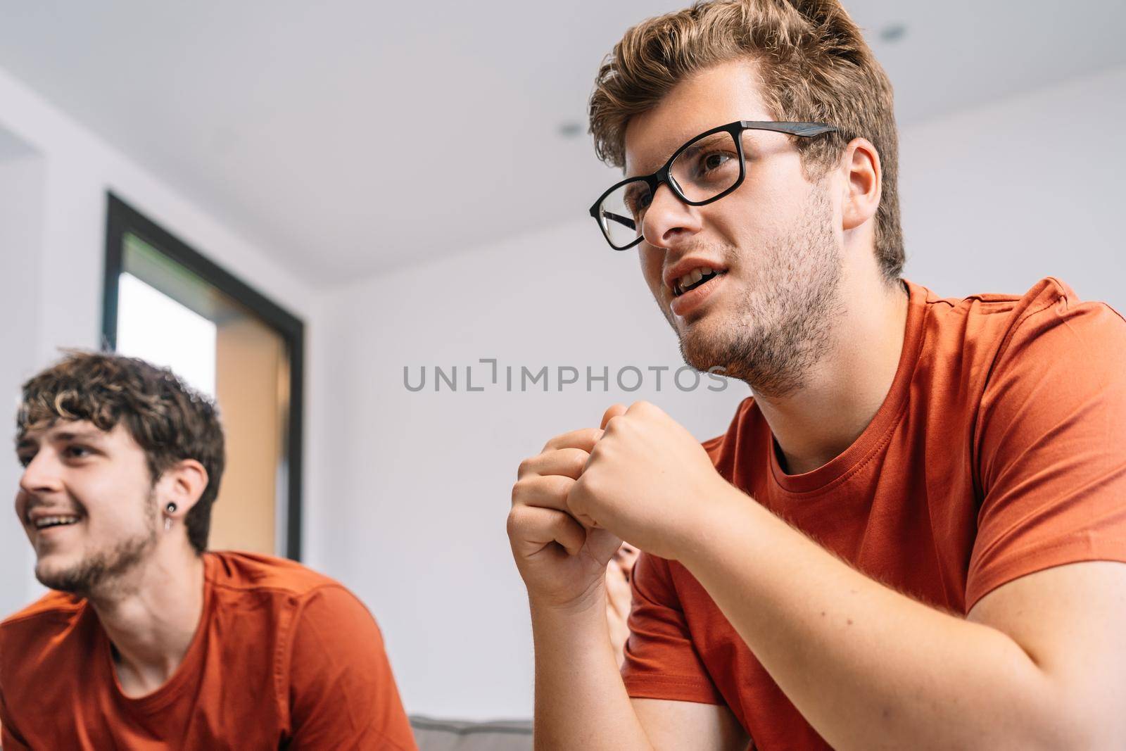 friends concentrating on watching e-sports on TV after their team's victory. group of young people partying at home. leisure concept. happy and cheerful. natural light in the living room at home. trumpet