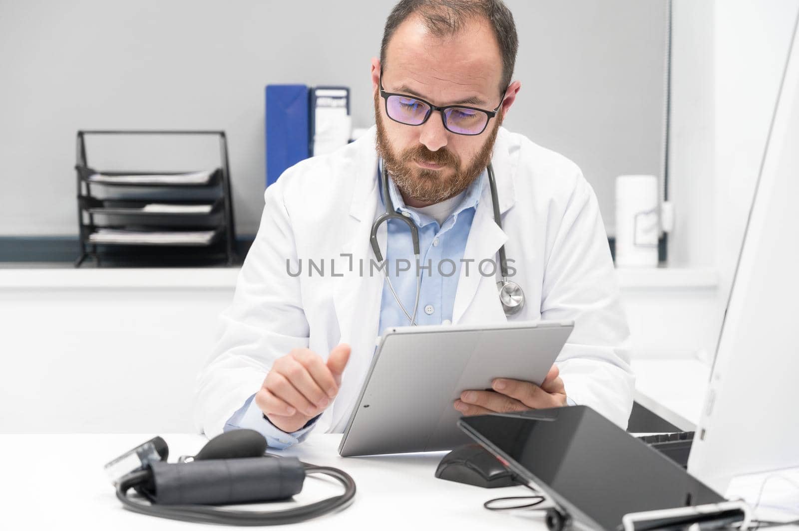 Doctor using his tablet computer at work by HERRAEZ