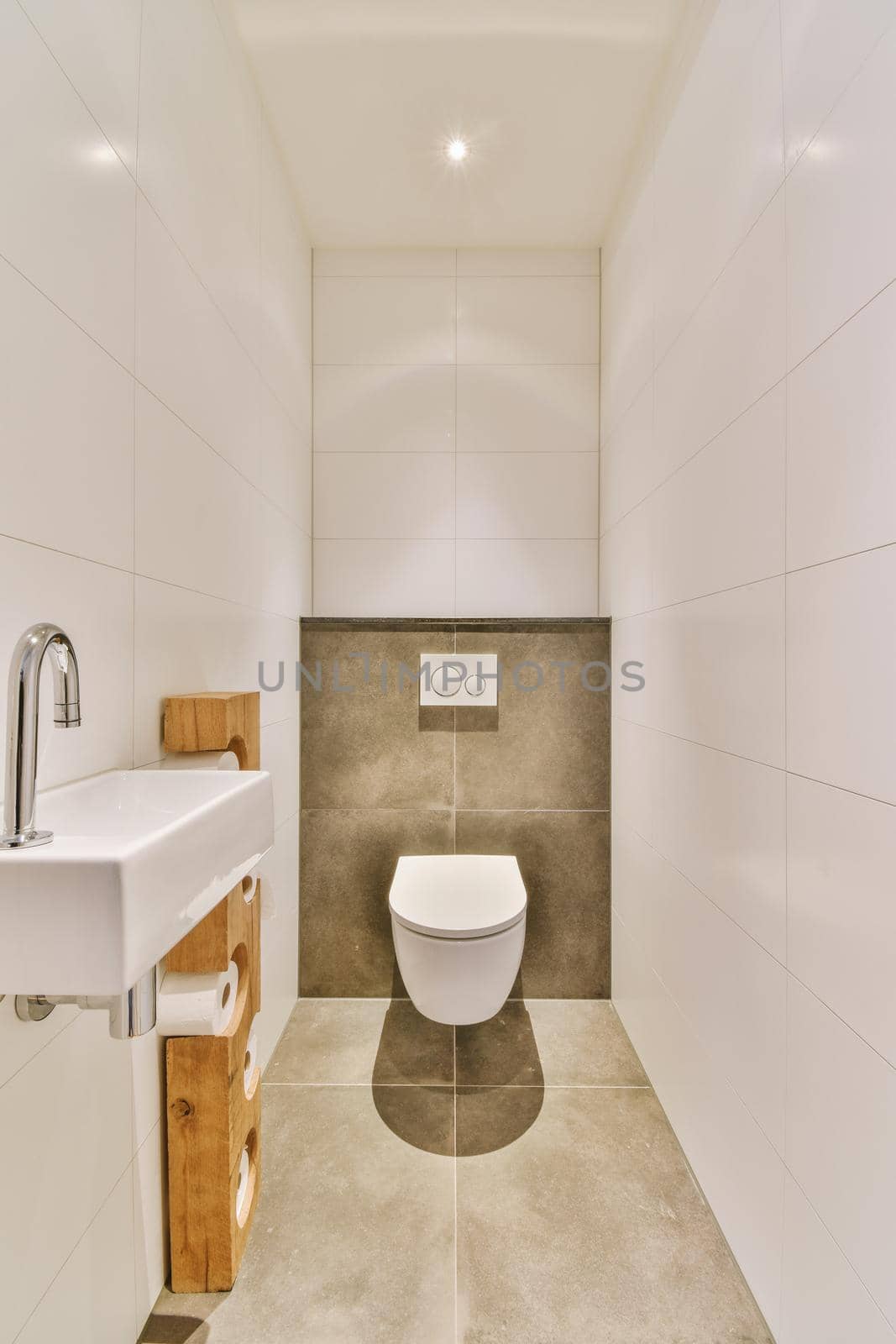 Interior of narrow restroom with sink and wall hung toilet with white walls and checkered floor