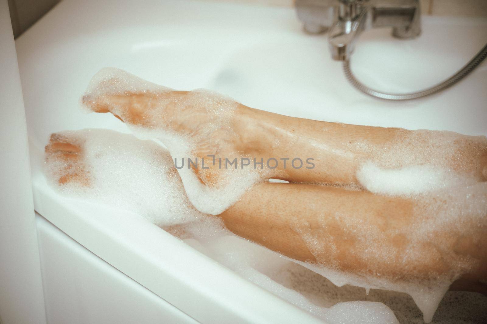 Women's feet in bath foam. View from above. Enjoy and relax in a spa hotel by Matiunina