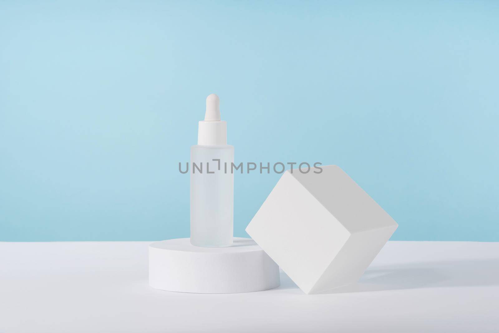 Serum cosmetic bottle with peptides and retinol on platform pedestal on blue background. Oil cosmetics transparent fashion product packaging with stylish props. Serum beauty dropper mock up by photolime