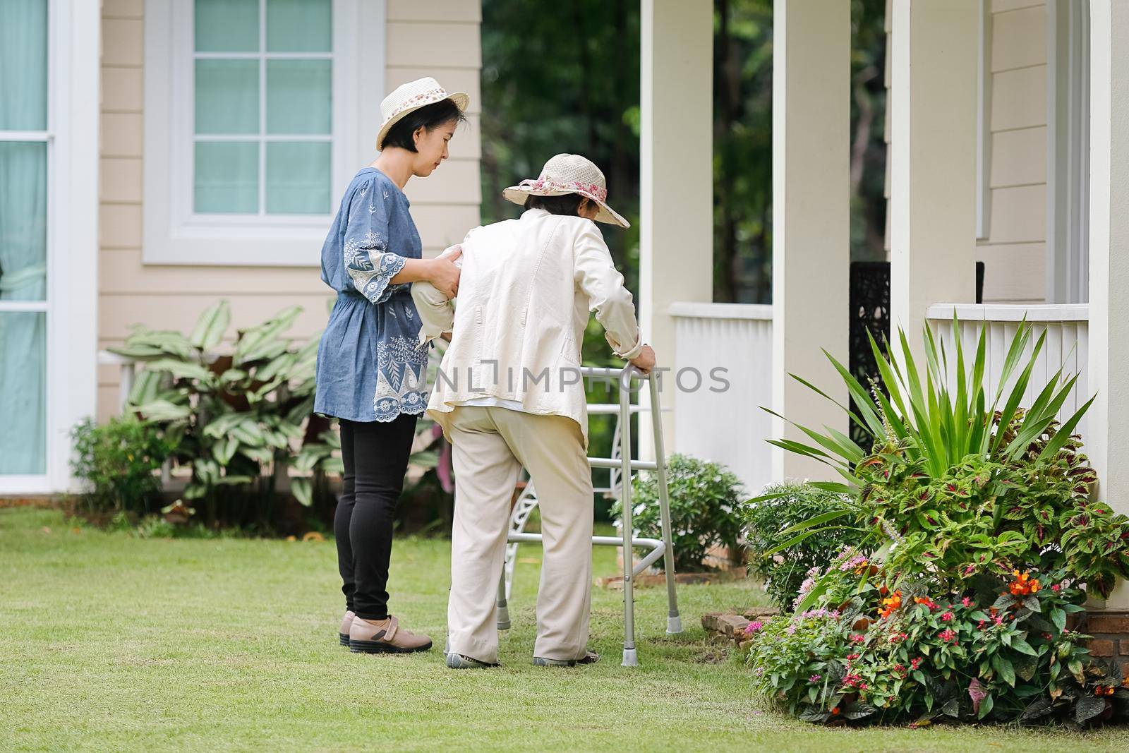 Elderly woman in physical therapy walking in backyard with daughter