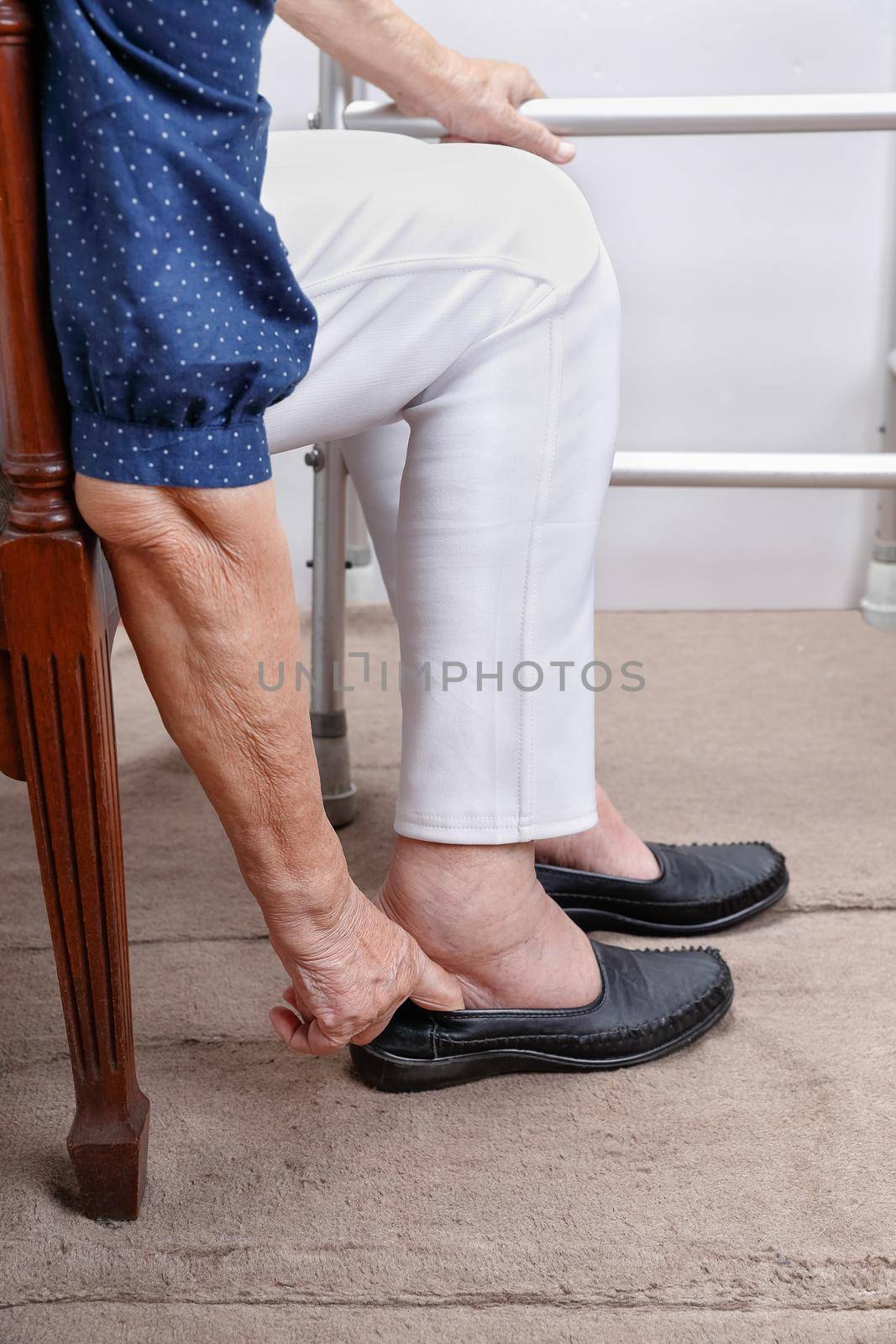 Elderly woman putting on shoes.