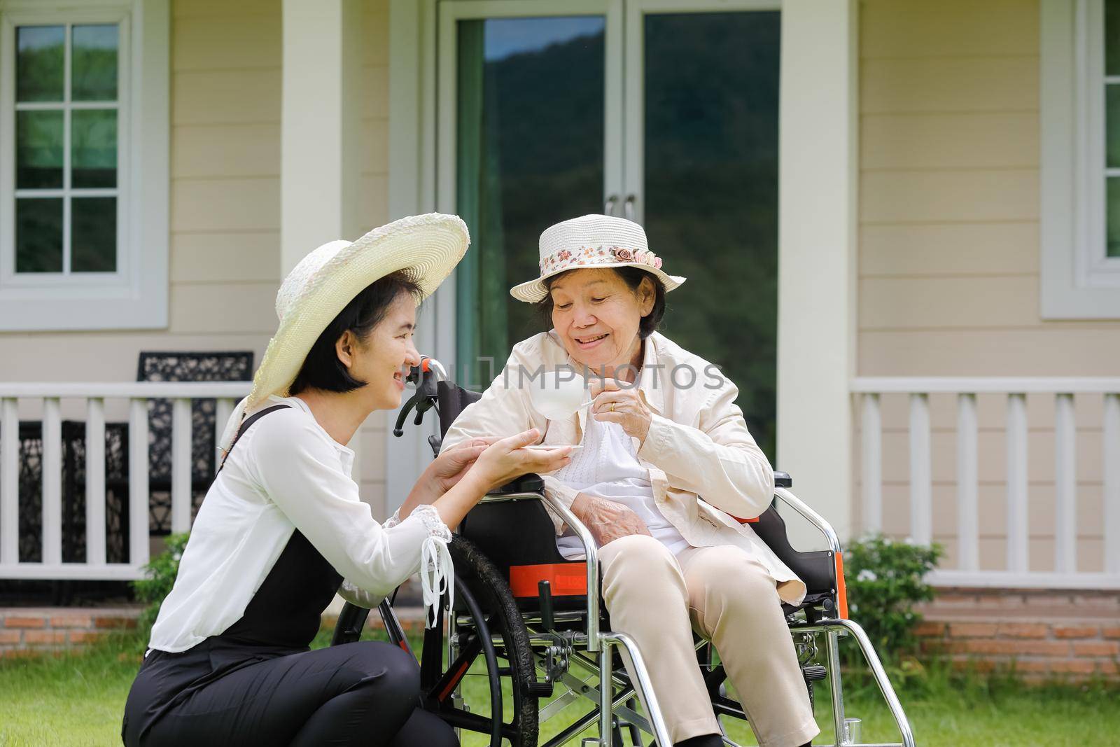 Elderly woman relax on wheelchair in backyard with daughter