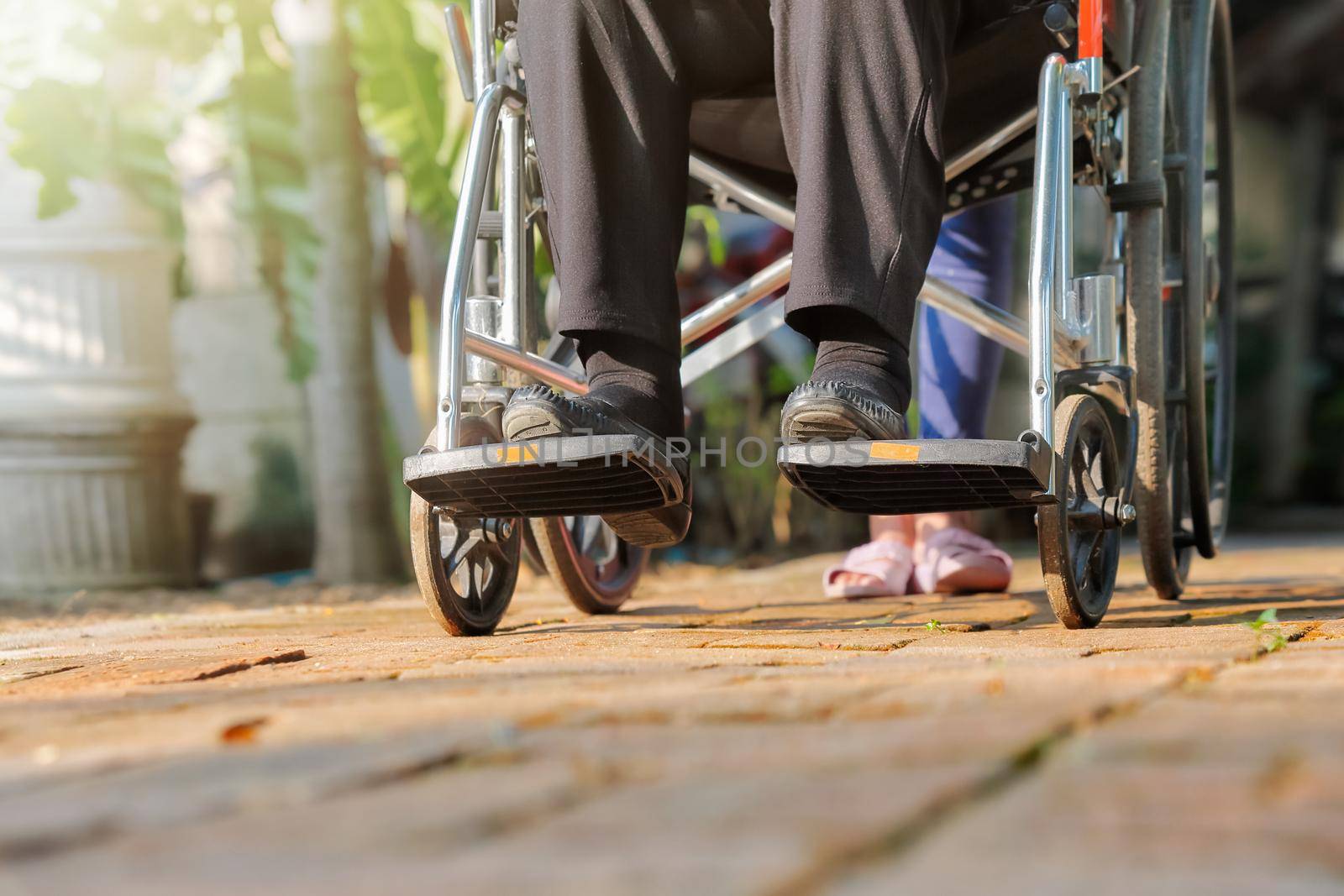 elderly woman in wheelchair walking with caregiver