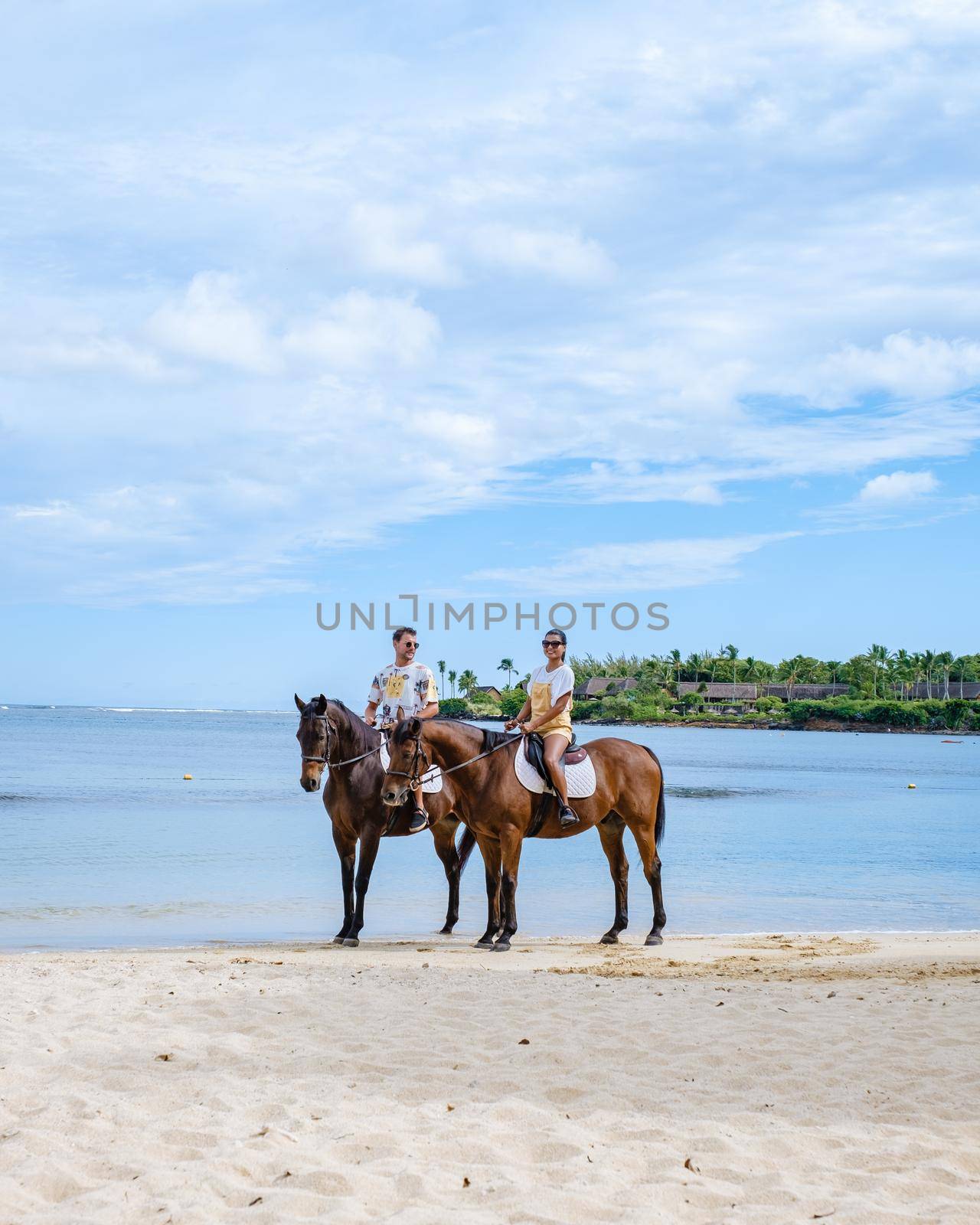 horse riding on the beach, man and woman on horse on the beach during luxury vacation in Mauritius by fokkebok