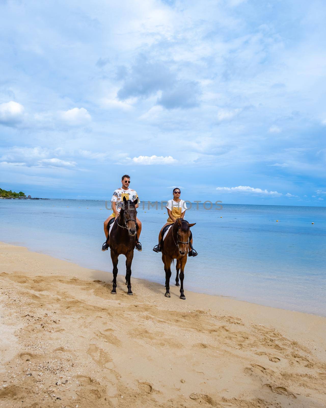 horse riding on the beach, man and woman on horse on the beach during luxury vacation in Mauritius by fokkebok