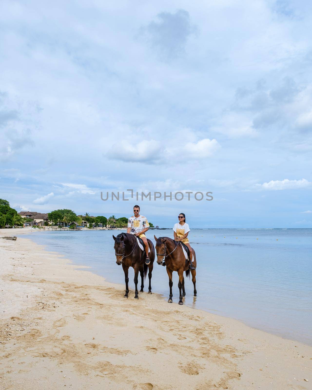 horse riding on the beach, man and woman on horse on the beach during luxury vacation in Mauritius by fokkebok