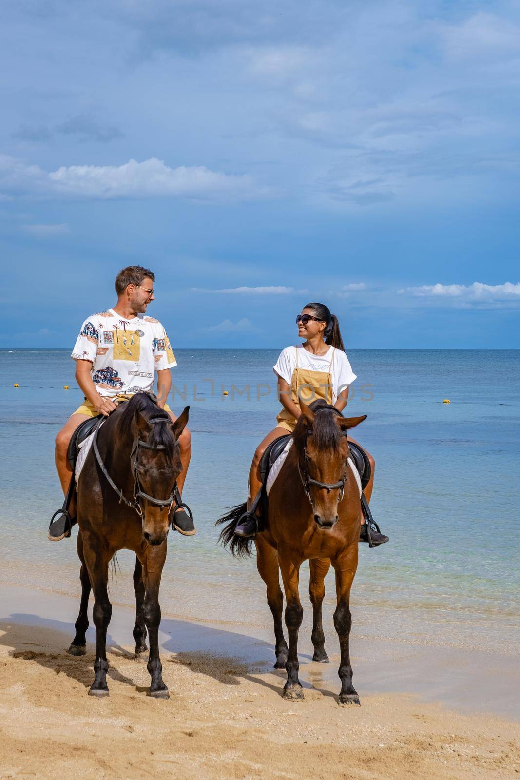 horse riding on the beach, man and woman on a horse on the beach during a luxury vacation in Mauritius.