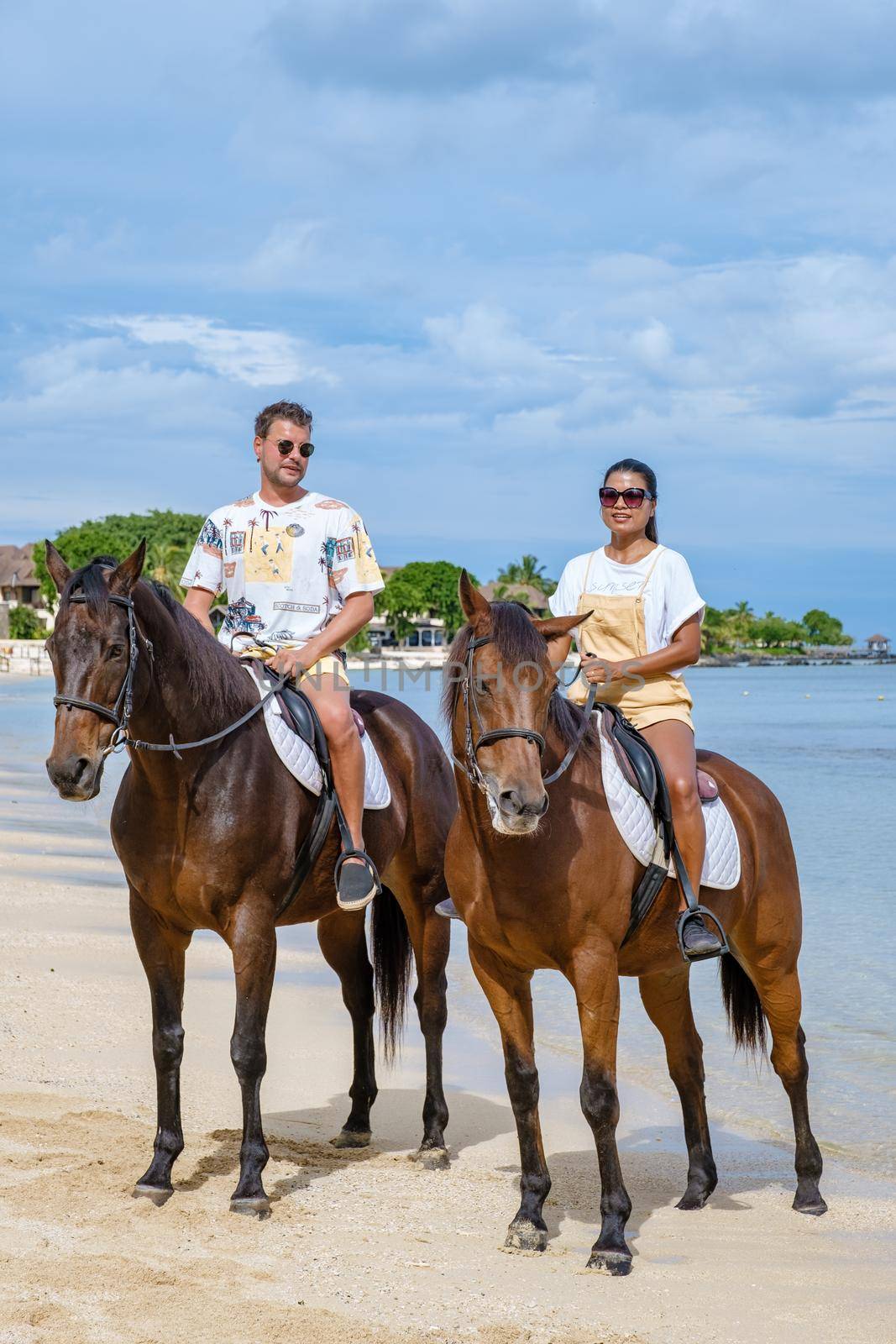horse riding on the beach, man and woman on a horse on the beach during a luxury vacation in Mauritius.