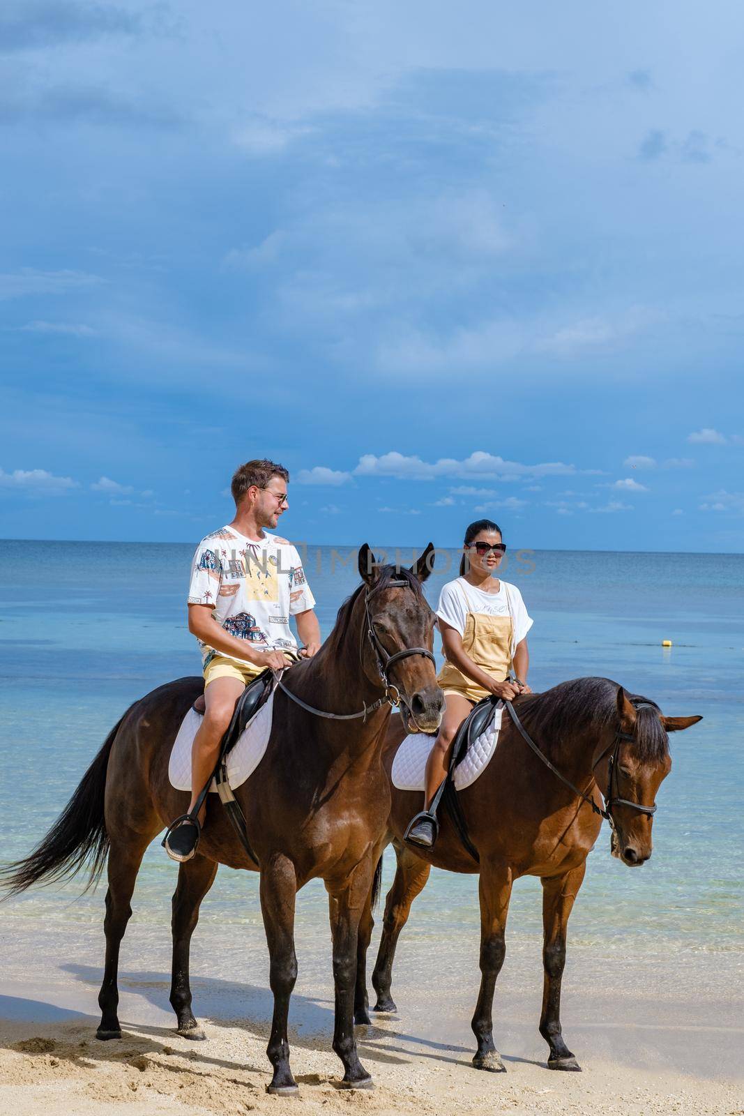 horse riding on the beach, man and woman on a horse on the beach during a luxury vacation in Mauritius.