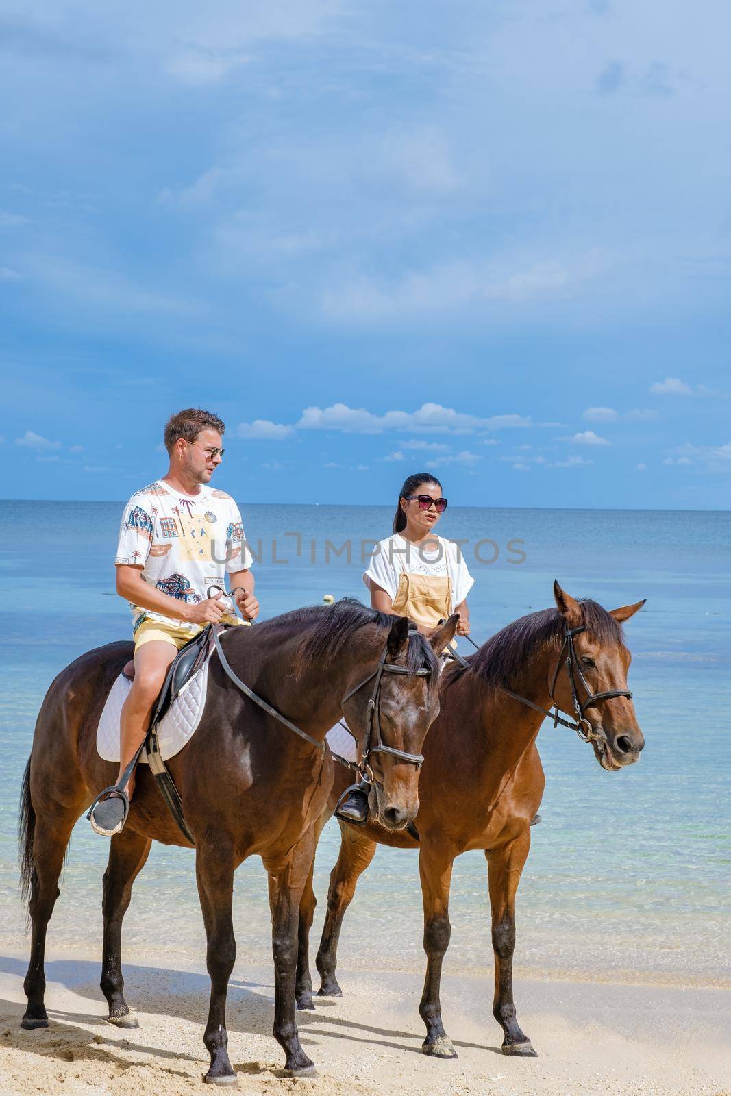 horse riding on the beach, man and woman on a horse on the beach during a luxury vacation in Mauritius.