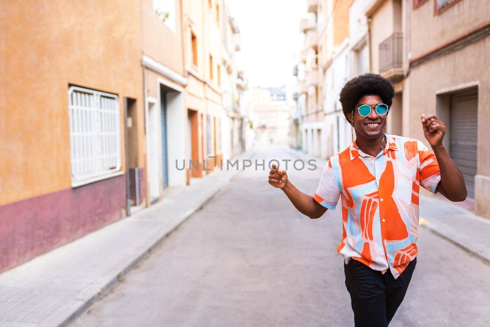 Happy young African American man dancing in the street celebrating and enjoying life. Having fun. Copy space. by Hoverstock