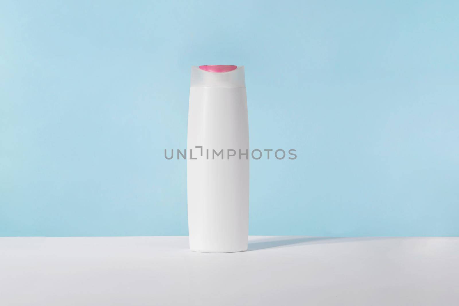 Shampoo white cosmetic bottle mockup on blue background. Hair product, bath soap or lotion packaging. Plastic cosmetics tube front view advertising mock up. Body hygiene cream by photolime