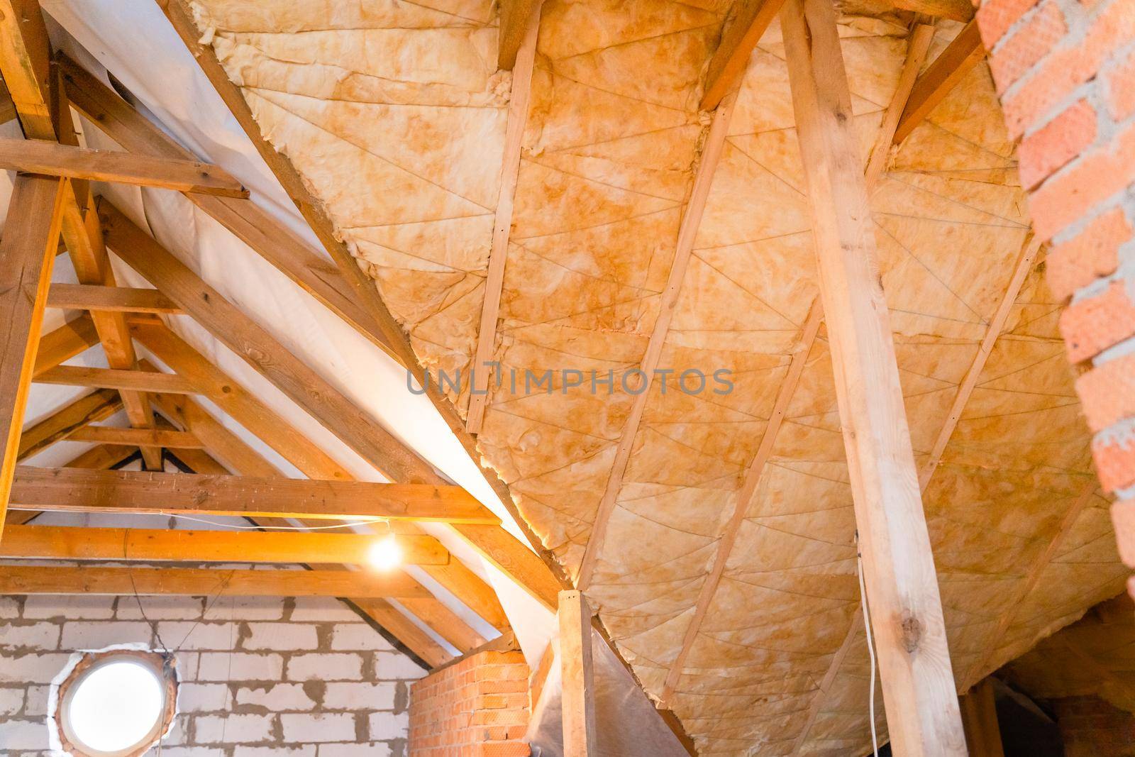 Glass roof insulation. Twine plastic thread supports the insulation between the rafters. Large non-insulated roof