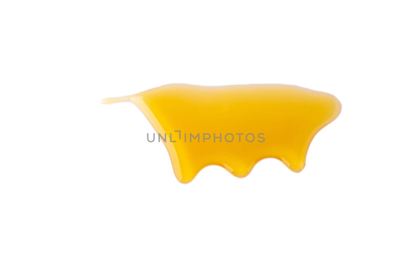 Isolated golden maple syrup flowing down on horizontal white background, copy space. Natural sweet caramel liquid studio shot. Yellow splash of stain nectar. Melting glossy sauce