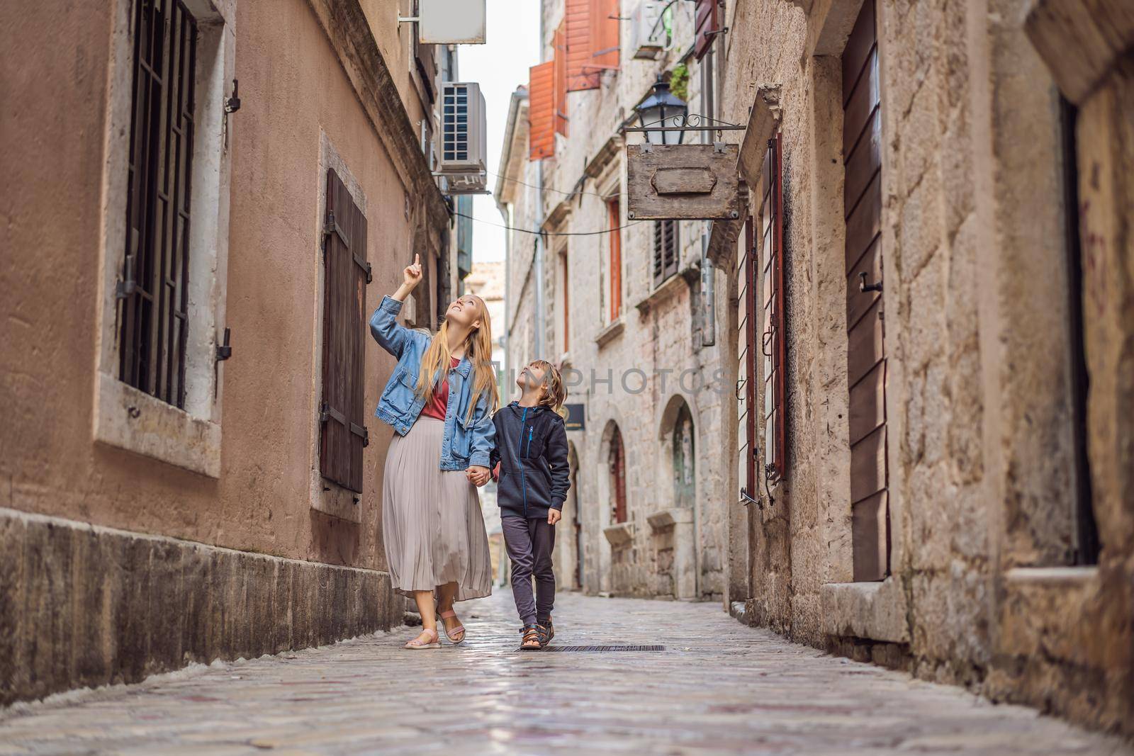 Mom and son travelers enjoying Colorful street in Old town of Kotor on a sunny day, Montenegro. Travel to Montenegro concept.