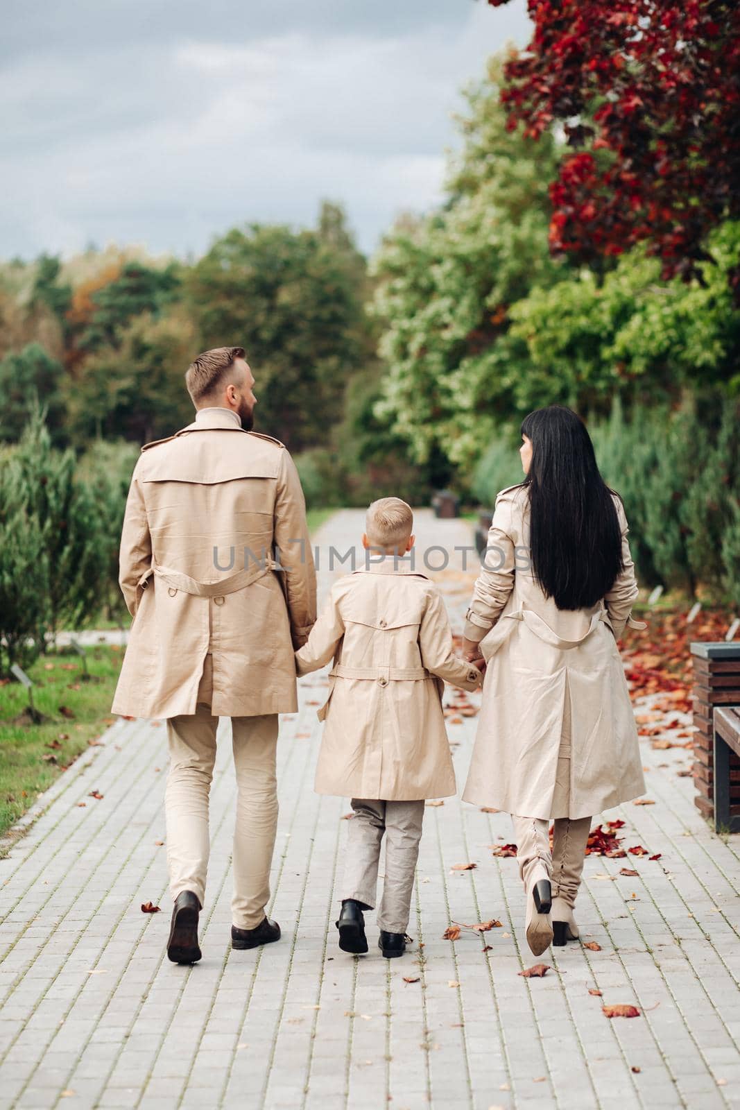 A happy family is walking in the park. Mom, dad and son are chatting and walking. A stylish family. parents in love