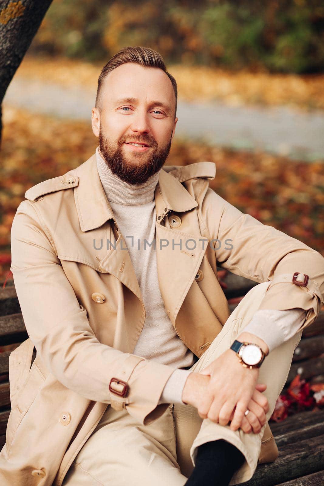 Portrait of a man in the forest with autumn leaves behind him.