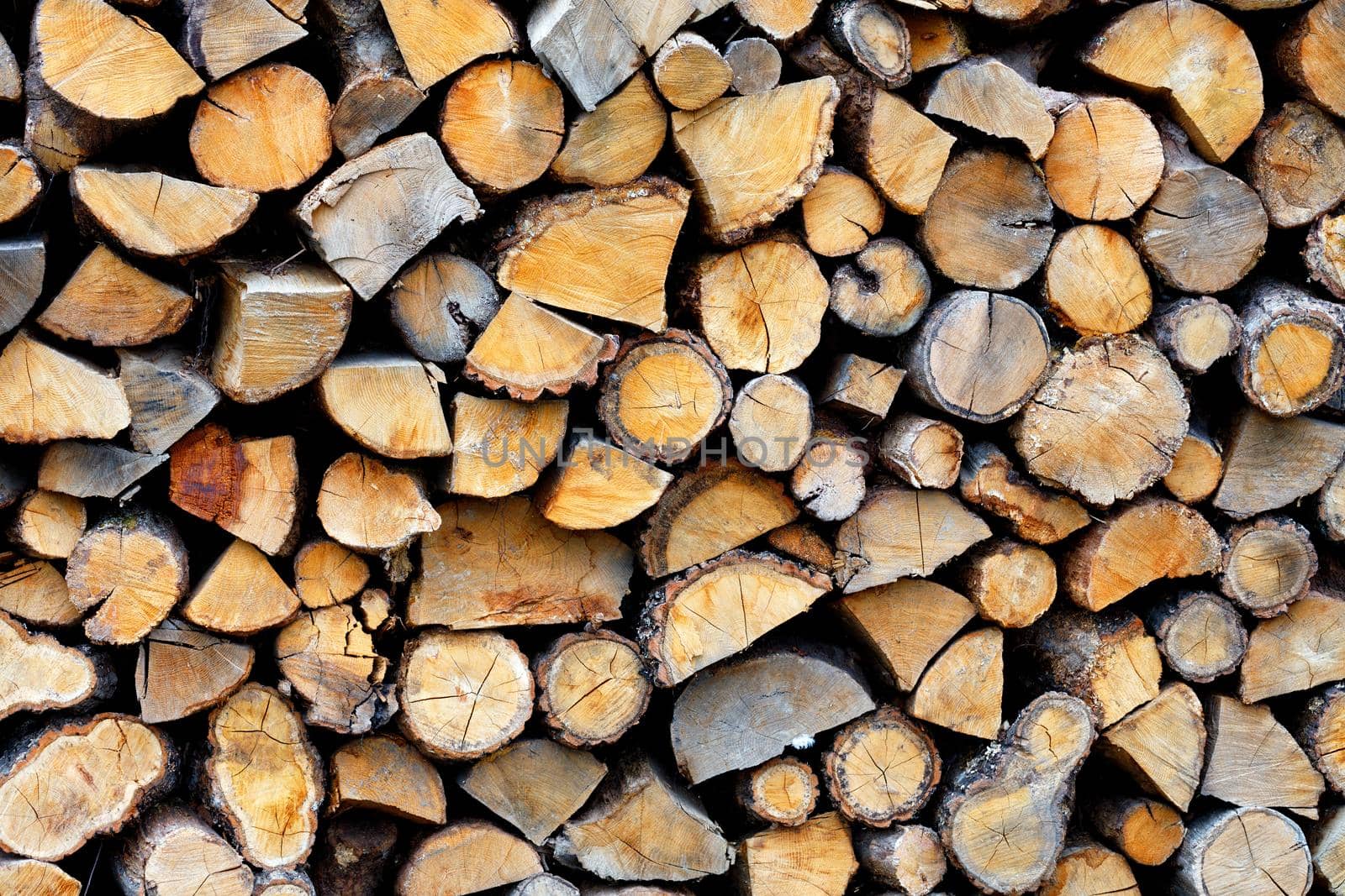 Stacked firewood close up, wood texture. A wall of firewood, a background of dry chopped firewood.