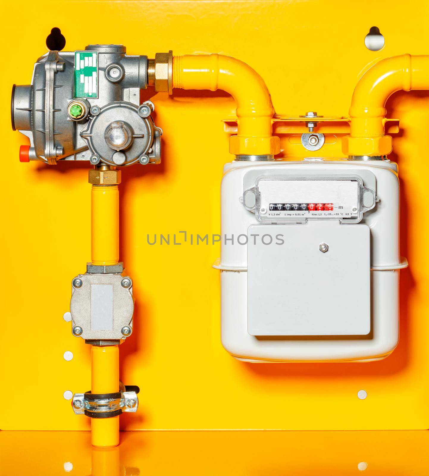 Gas meter, reducer and pipes mounted on a yellow background wall, copy space.