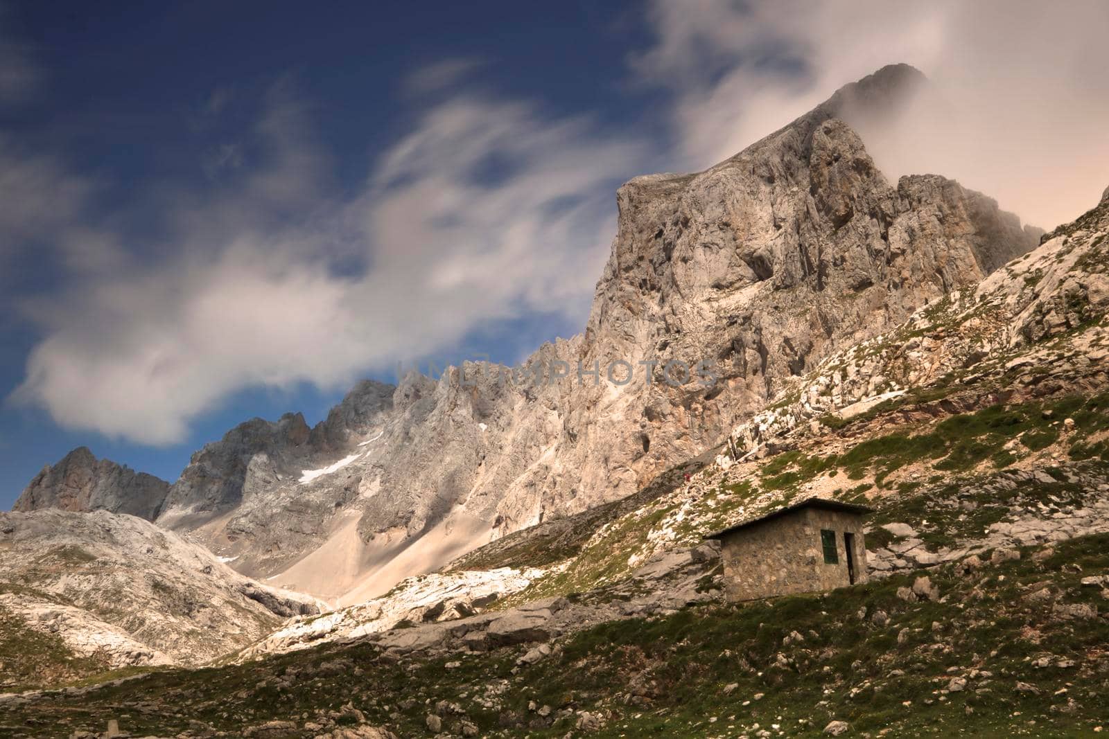 Landscape showing mountains and a small refuge under a cloudy sky in Fuente De in Spanish Picos de Europa mountain range