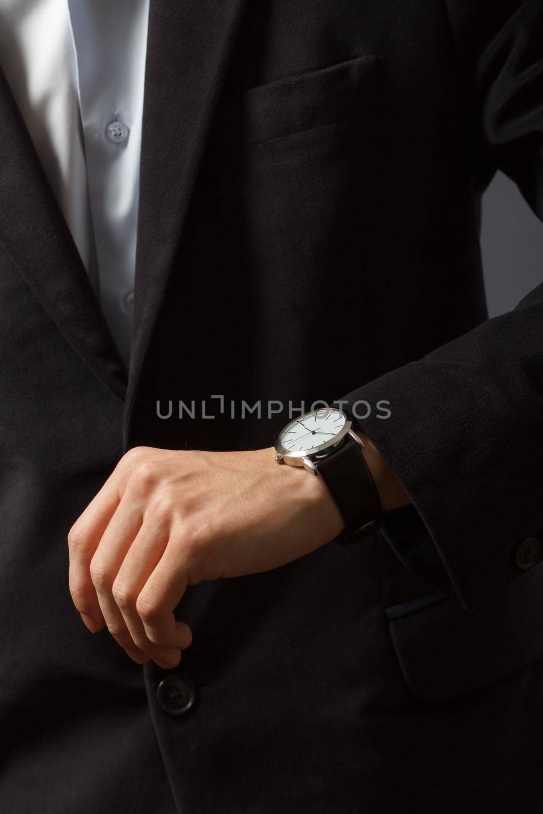 Man in a suit is standing and looking at his watch
