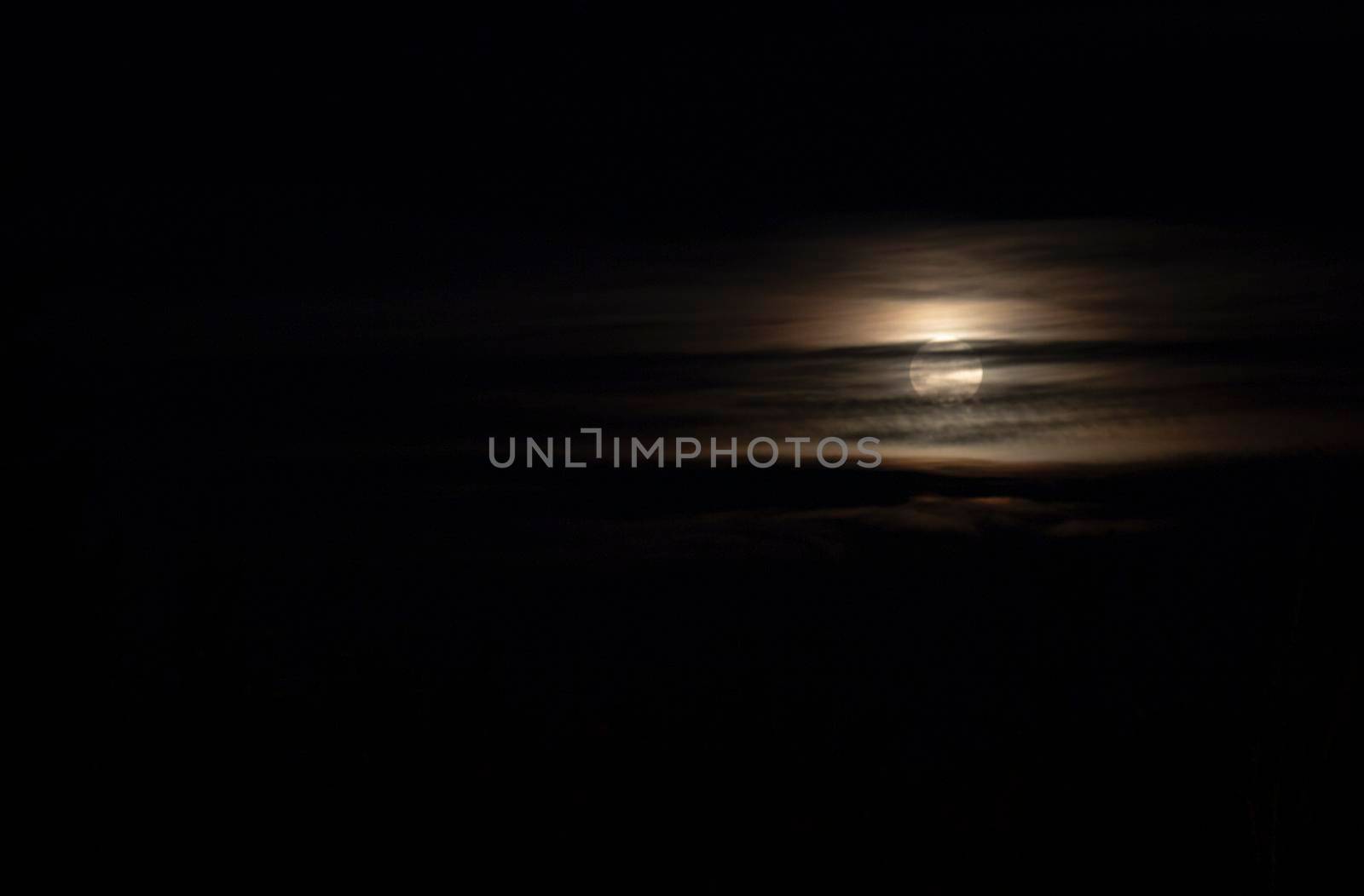 Full moon behind some clouds in a dark night