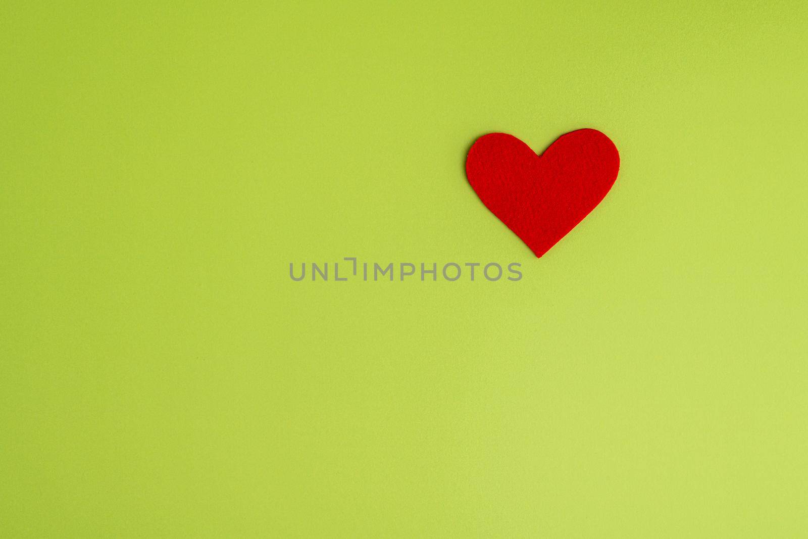 Red heart shaped cutout on green background. Concept of charity and healthcare donation. Love design element. Horizontal, top view, copy space. Valentine celebration