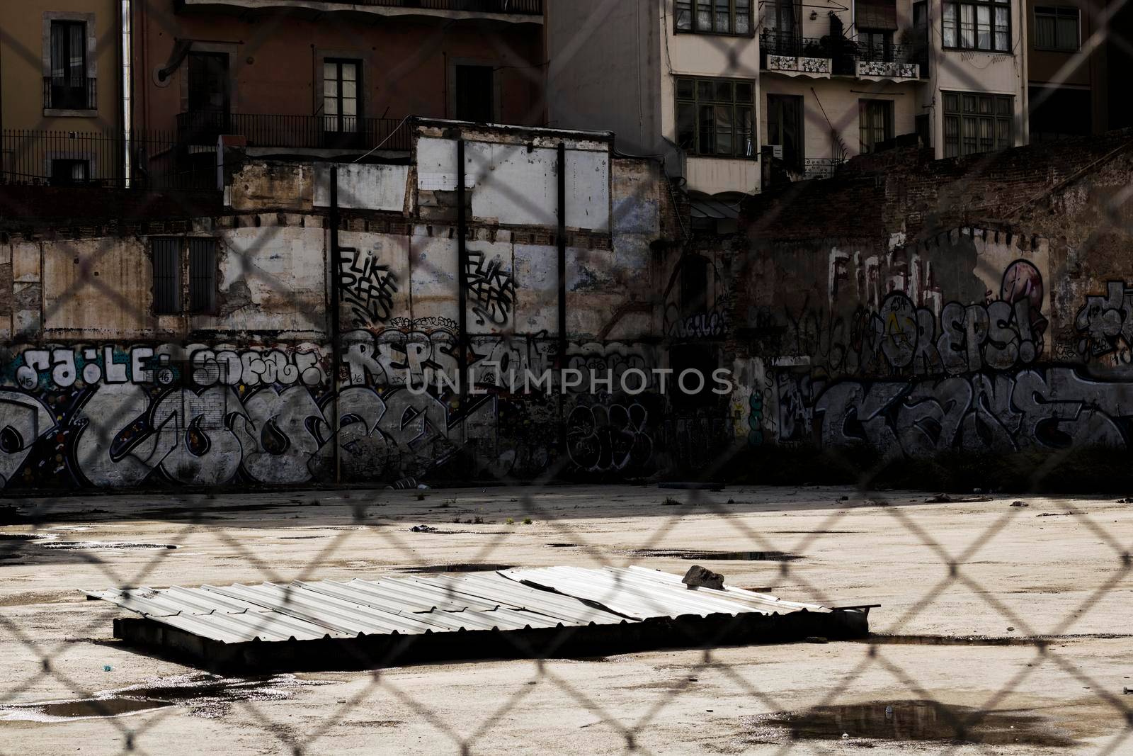 Street walls plenty of graffiti viewed through a fence in Barcelona